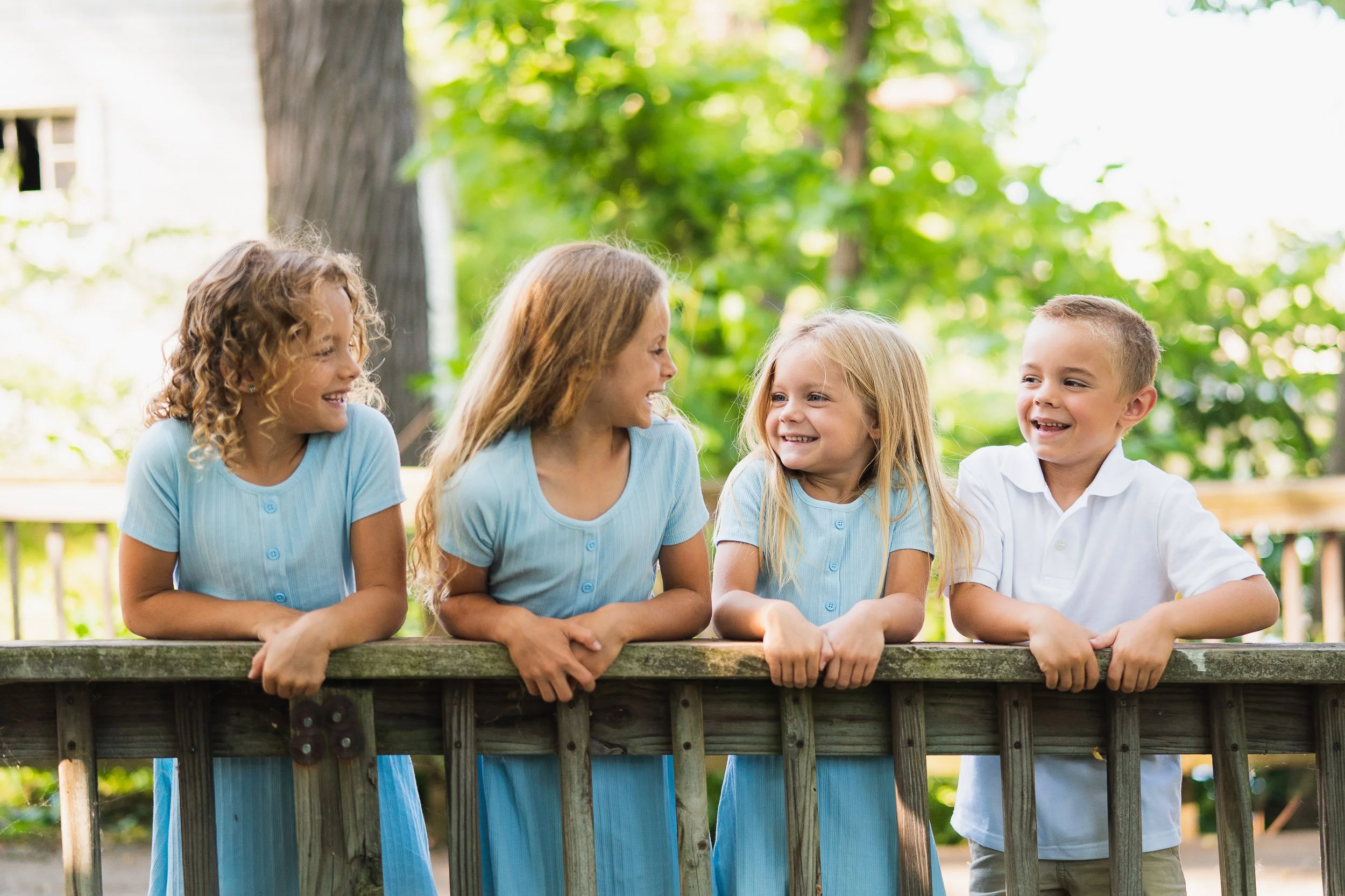 Group of children leaning over wooden bridge in summer clothes