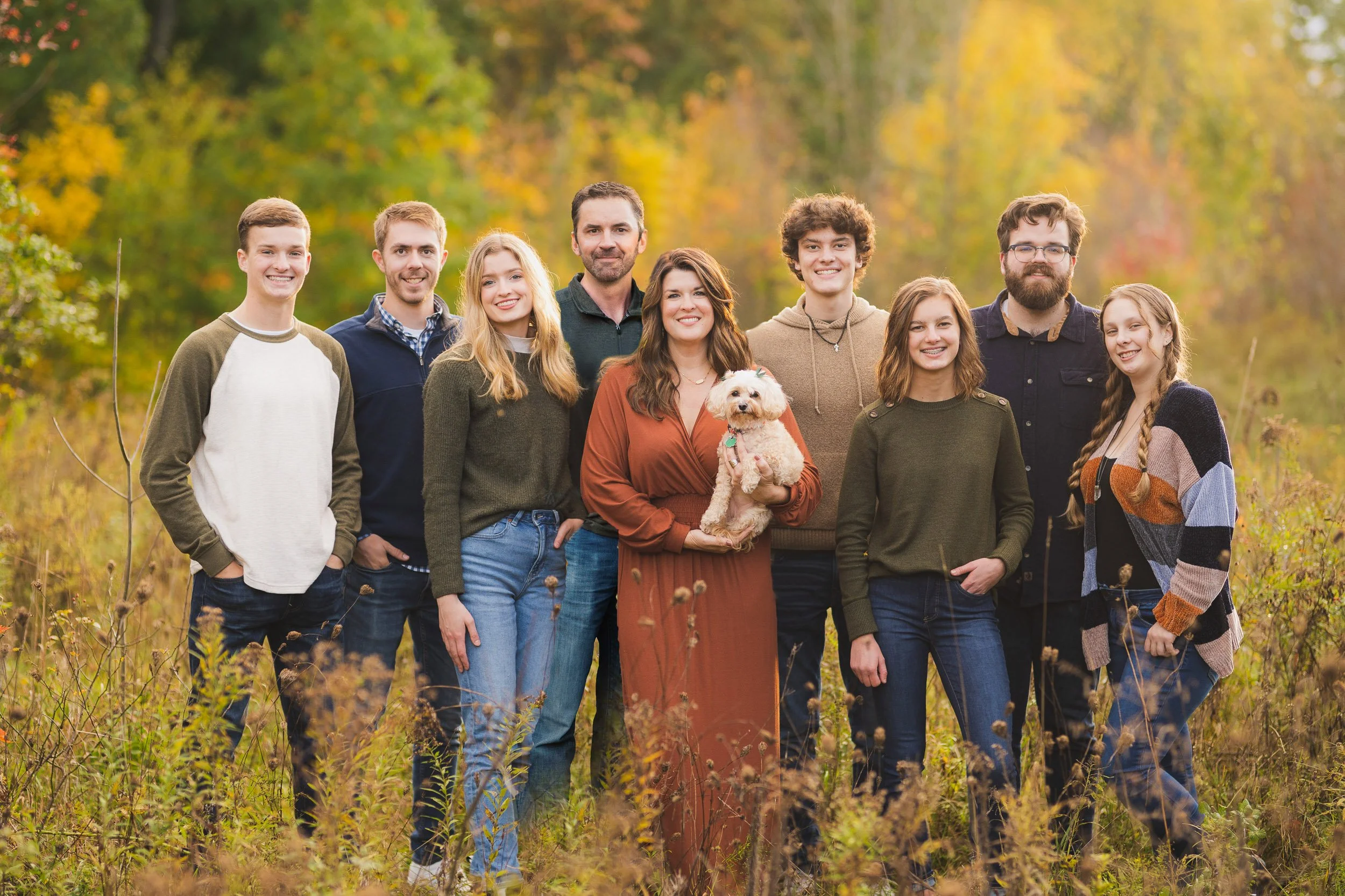 Large family portrait in field with fall colors and pet dog