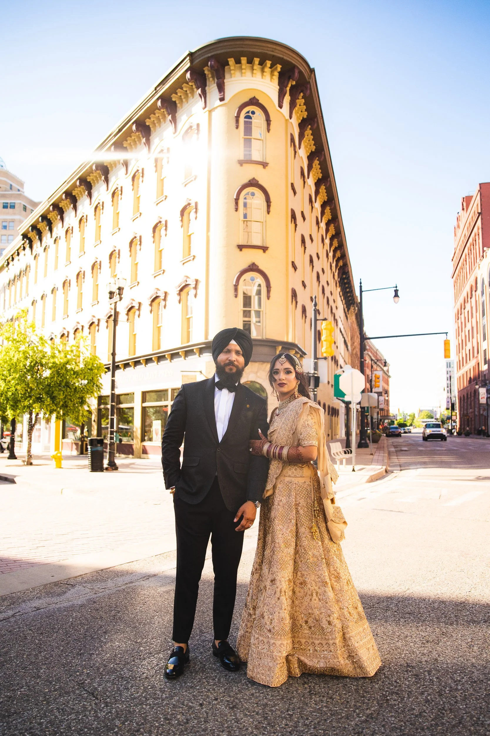 Bride and groom walking down city street in golden outfits