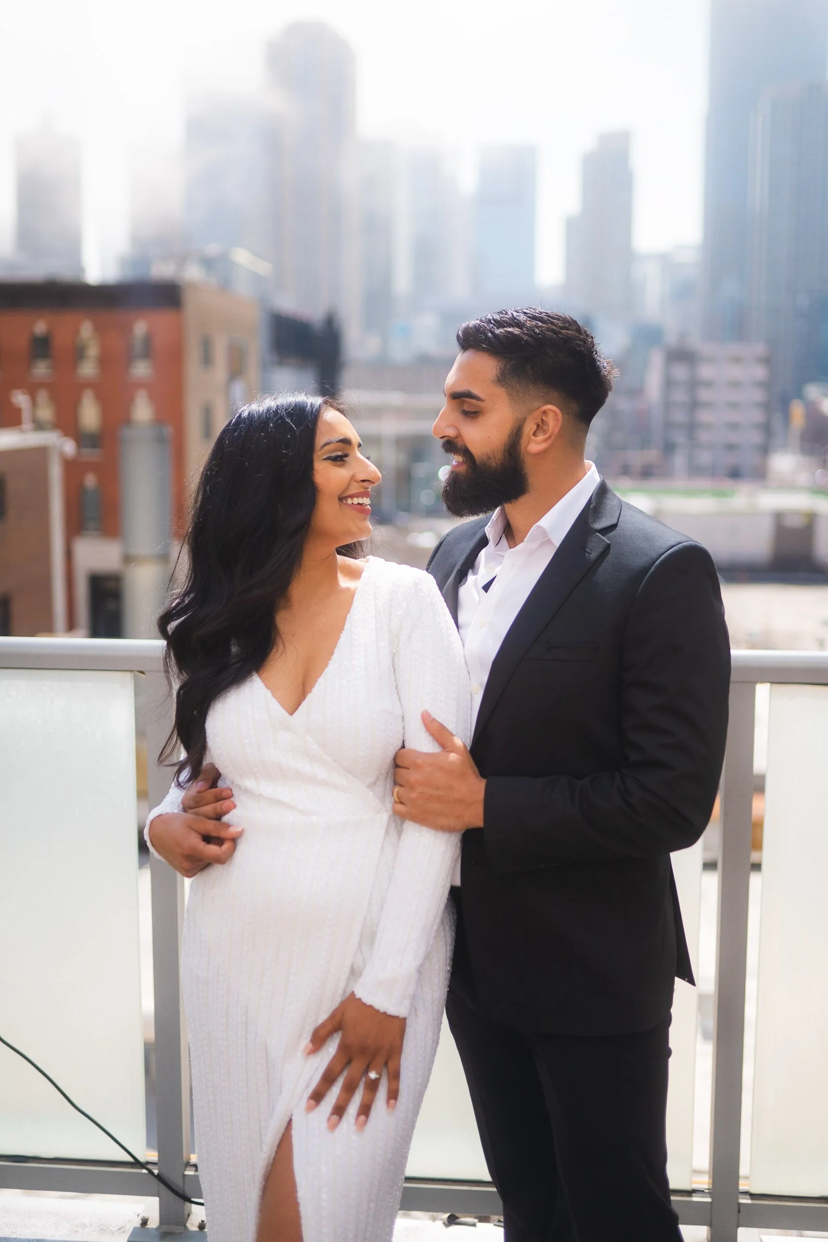 Engagement photo of couple on rooftop with city skyline