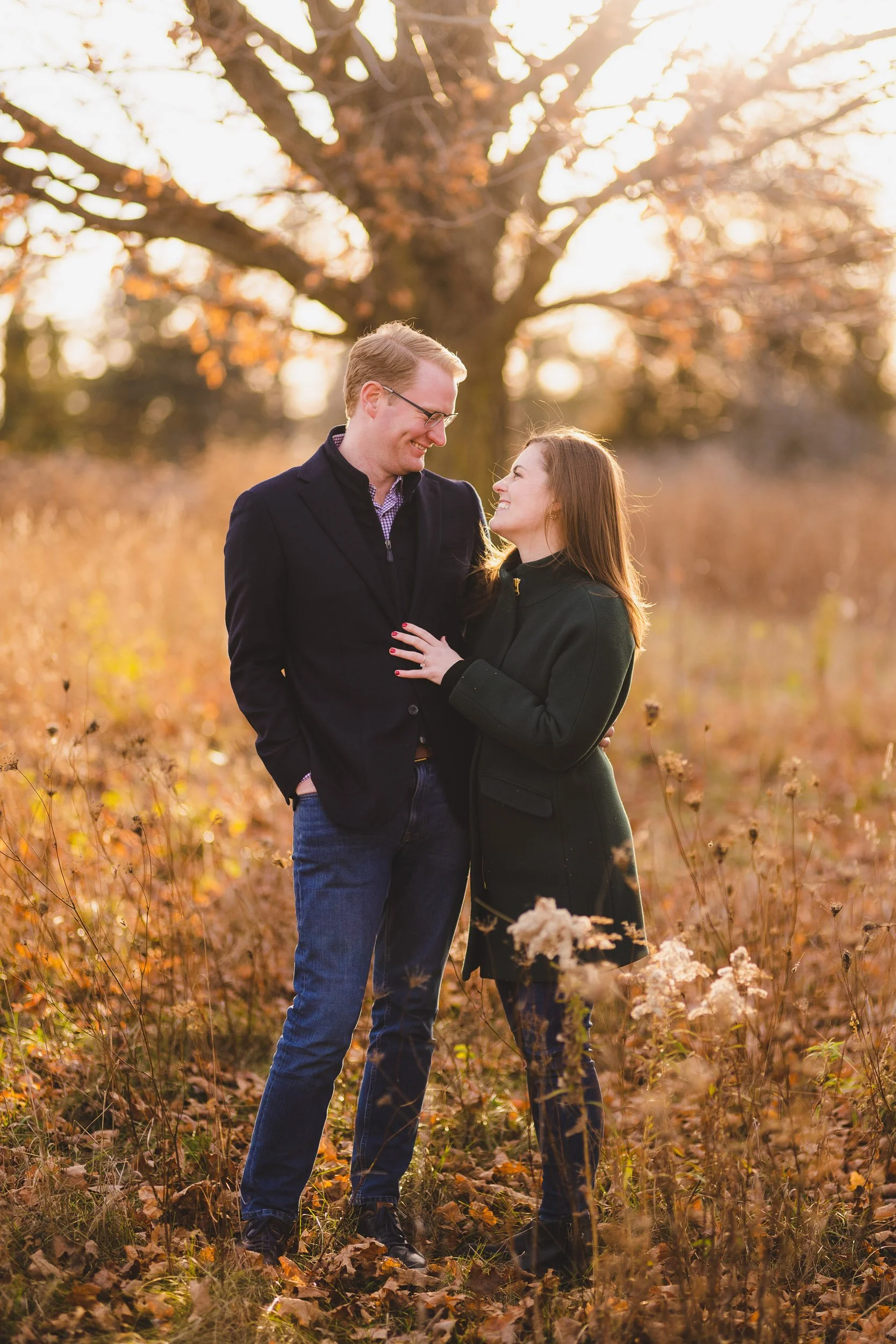 Engagement session in open field with tall grass at sunset