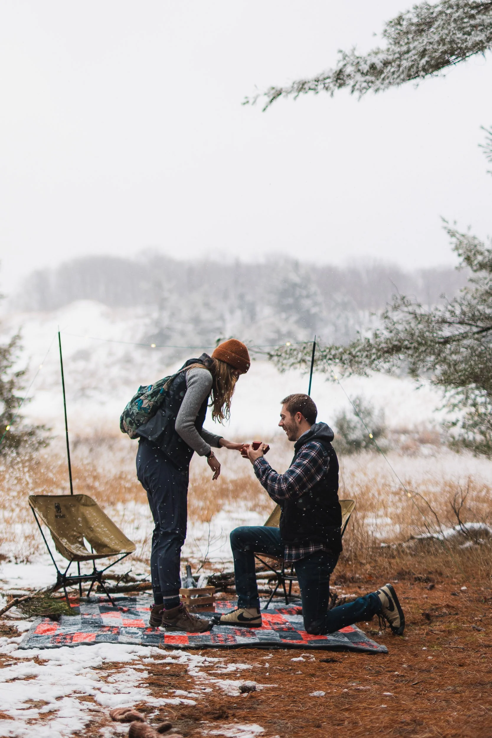 Outdoor winter proposal with hiking gear and snow-covered trees