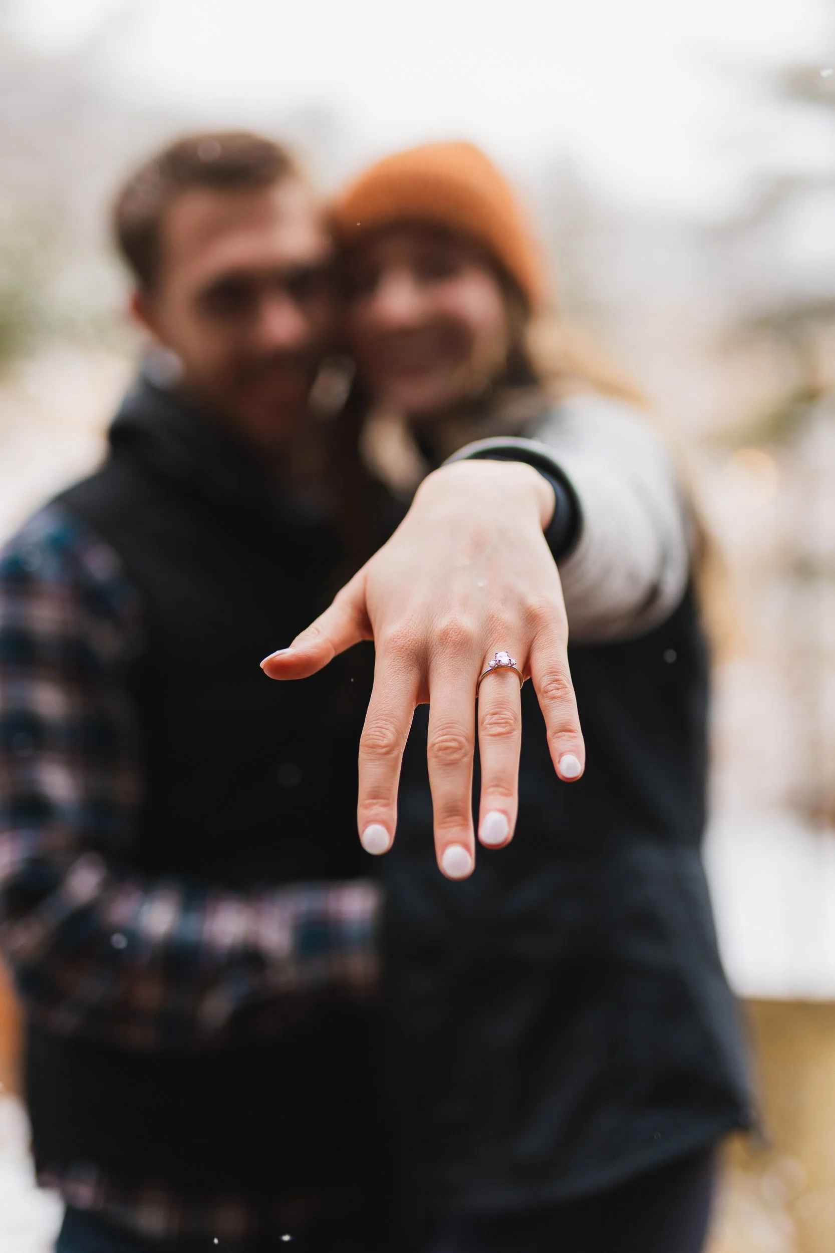 Couple showing off engagement ring with focus on hand