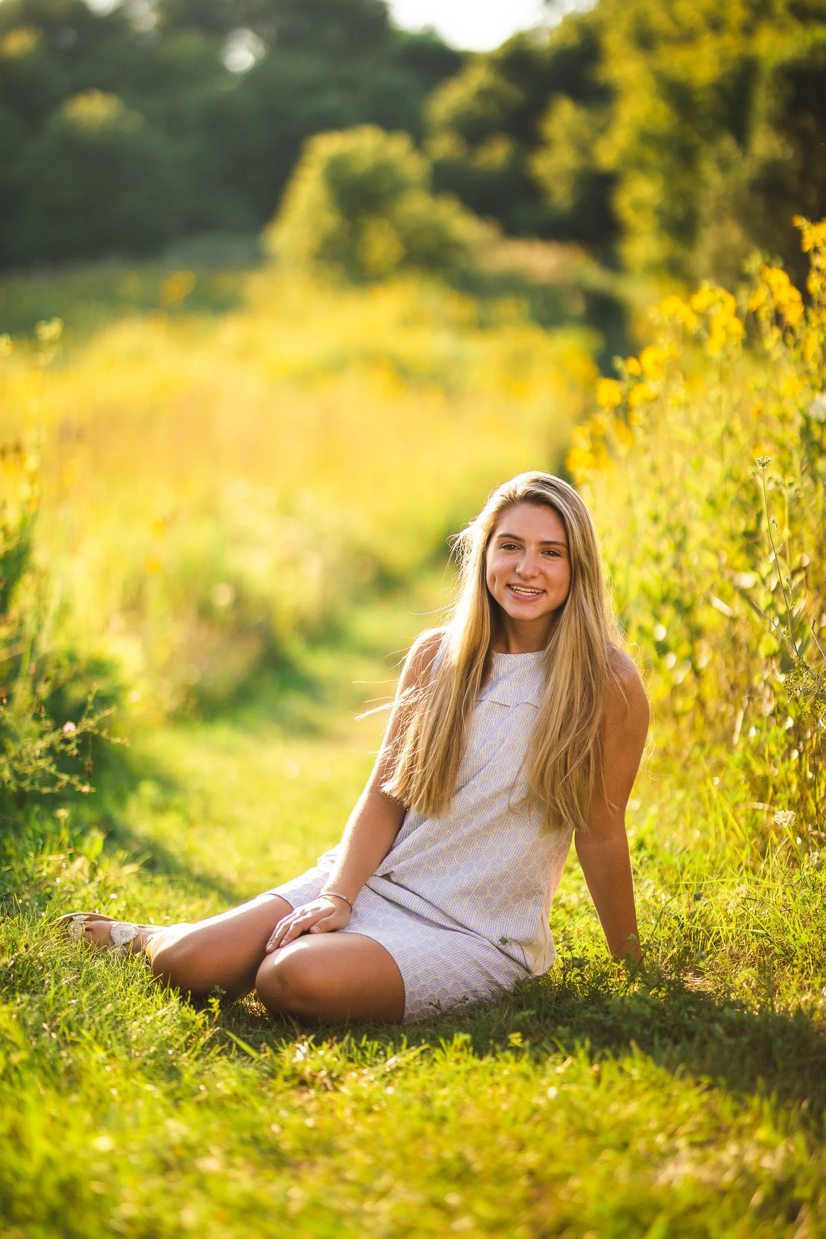 Senior portrait of girl sitting in wildflower field