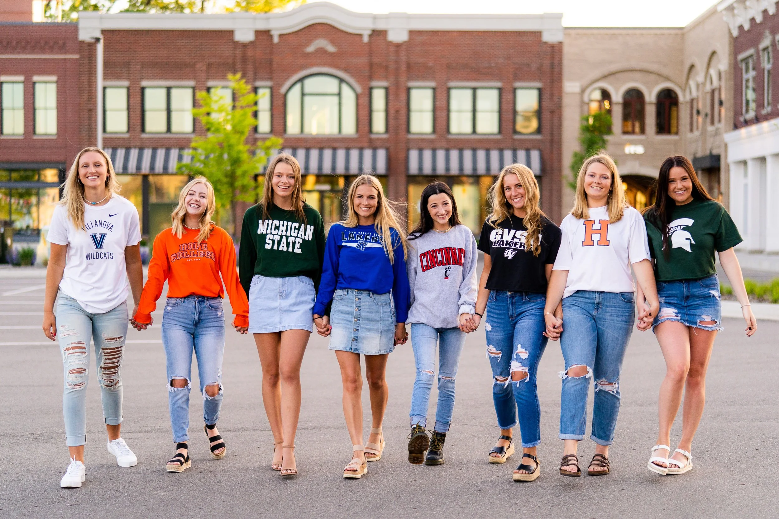 Girls walking in street wearing different college shirts