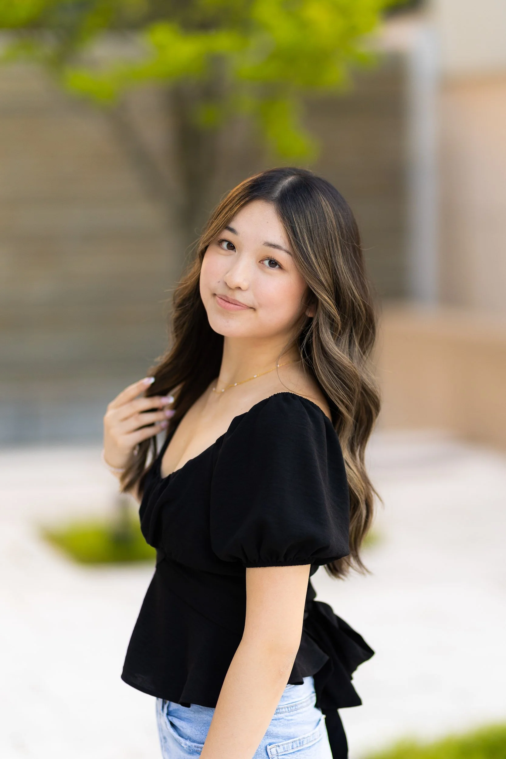 Young woman in black blouse smiling in soft natural light