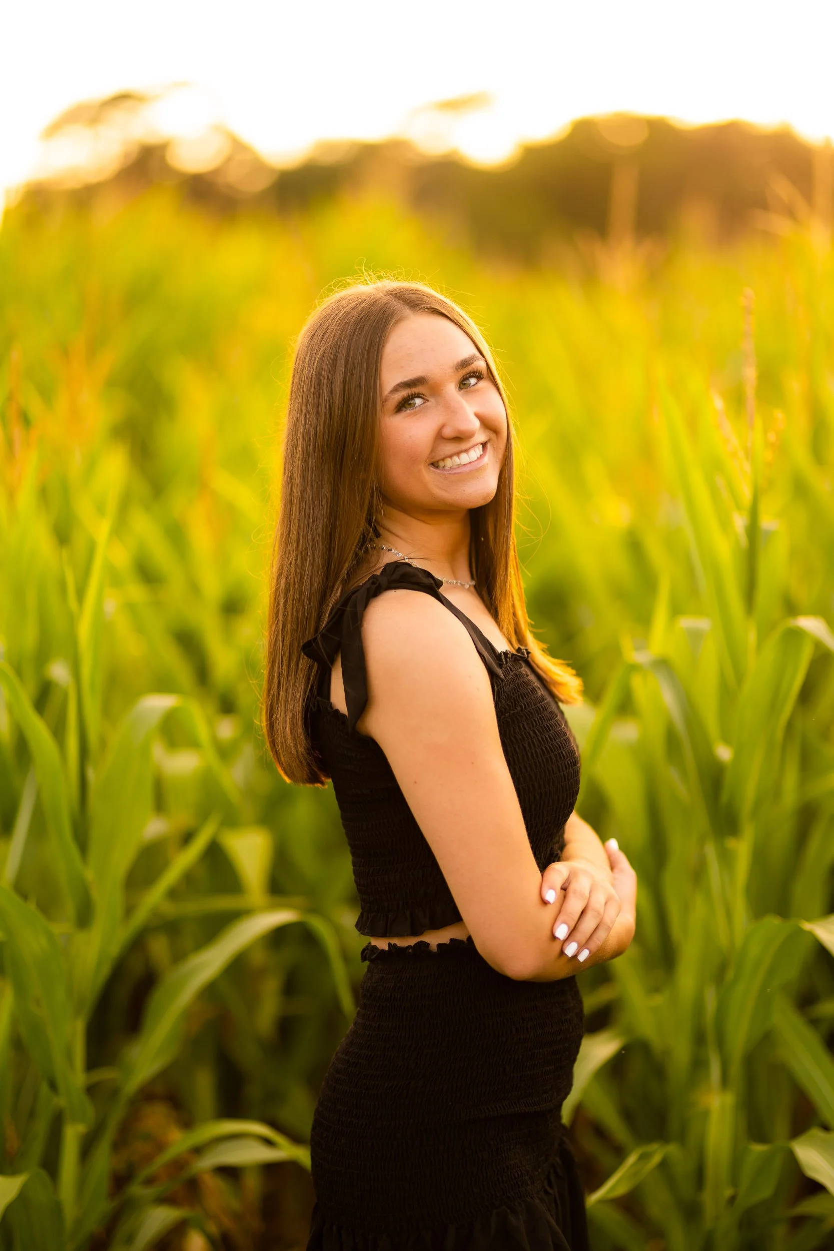 Young woman posing in cornfield at golden hour