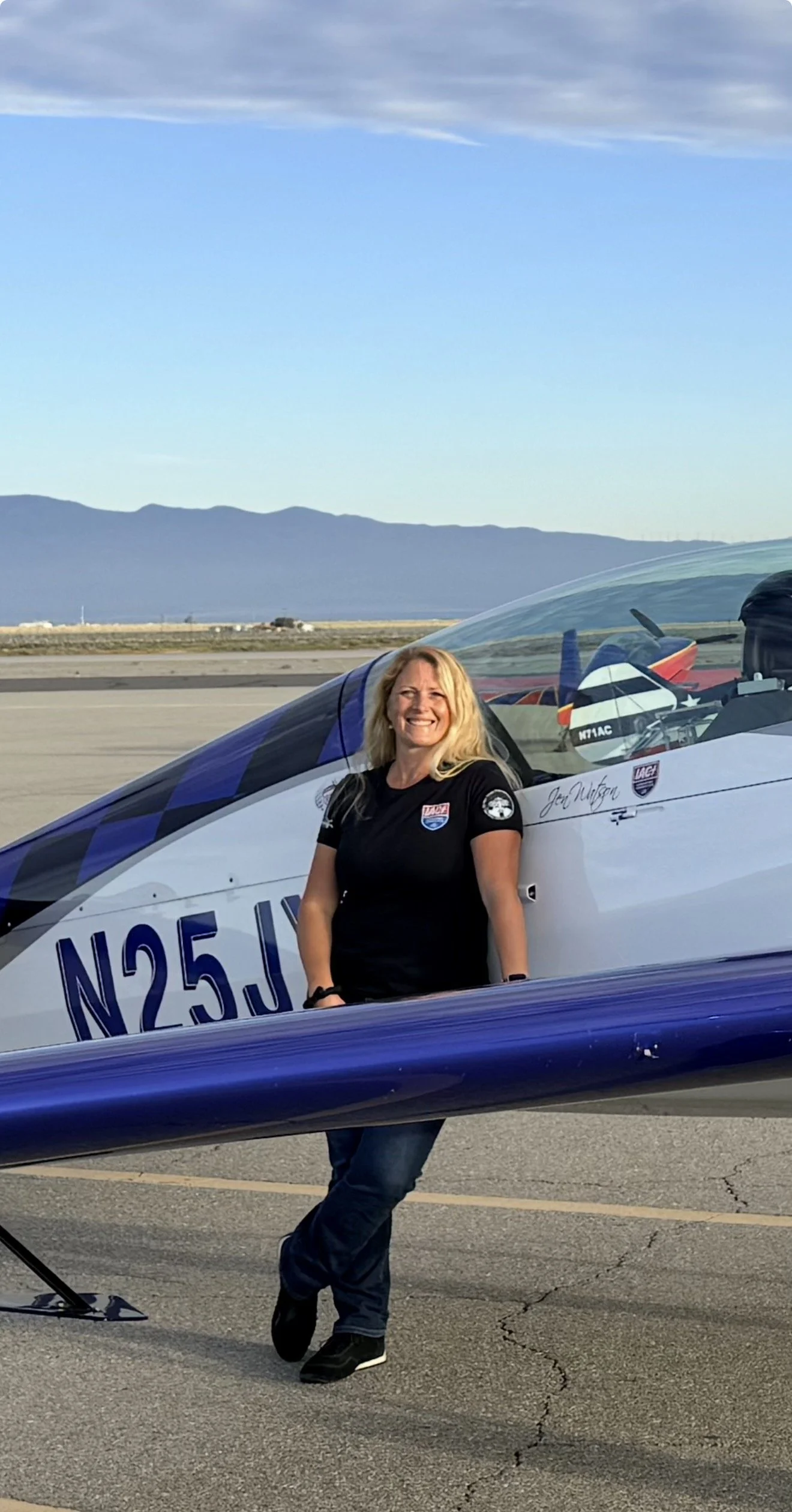 A woman standing next to an Extra 300L aerobatic airplane
