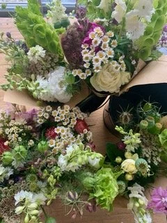 Multiple bouquets of mixed flowers including white roses, daisies, and greenery