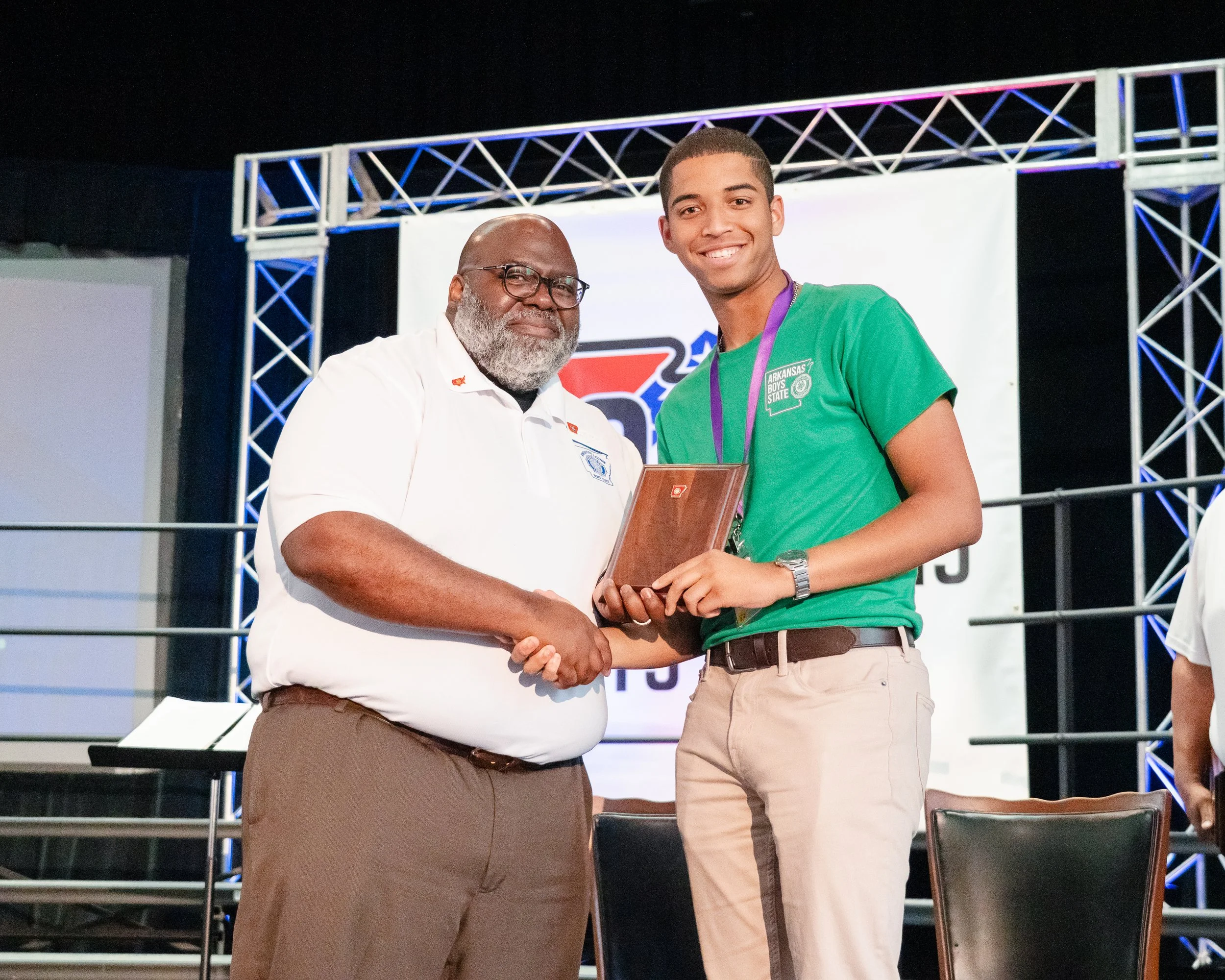 Plaque presentation with director and student shaking hands.
