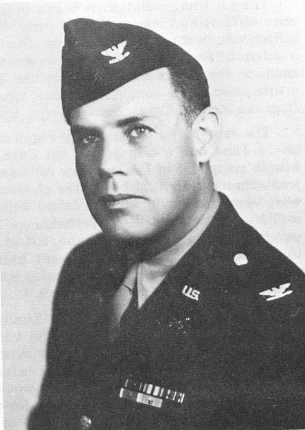 Black and white portrait of a man in a military uniform, wearing a hat with an eagle insignia, and displaying military ribbons.