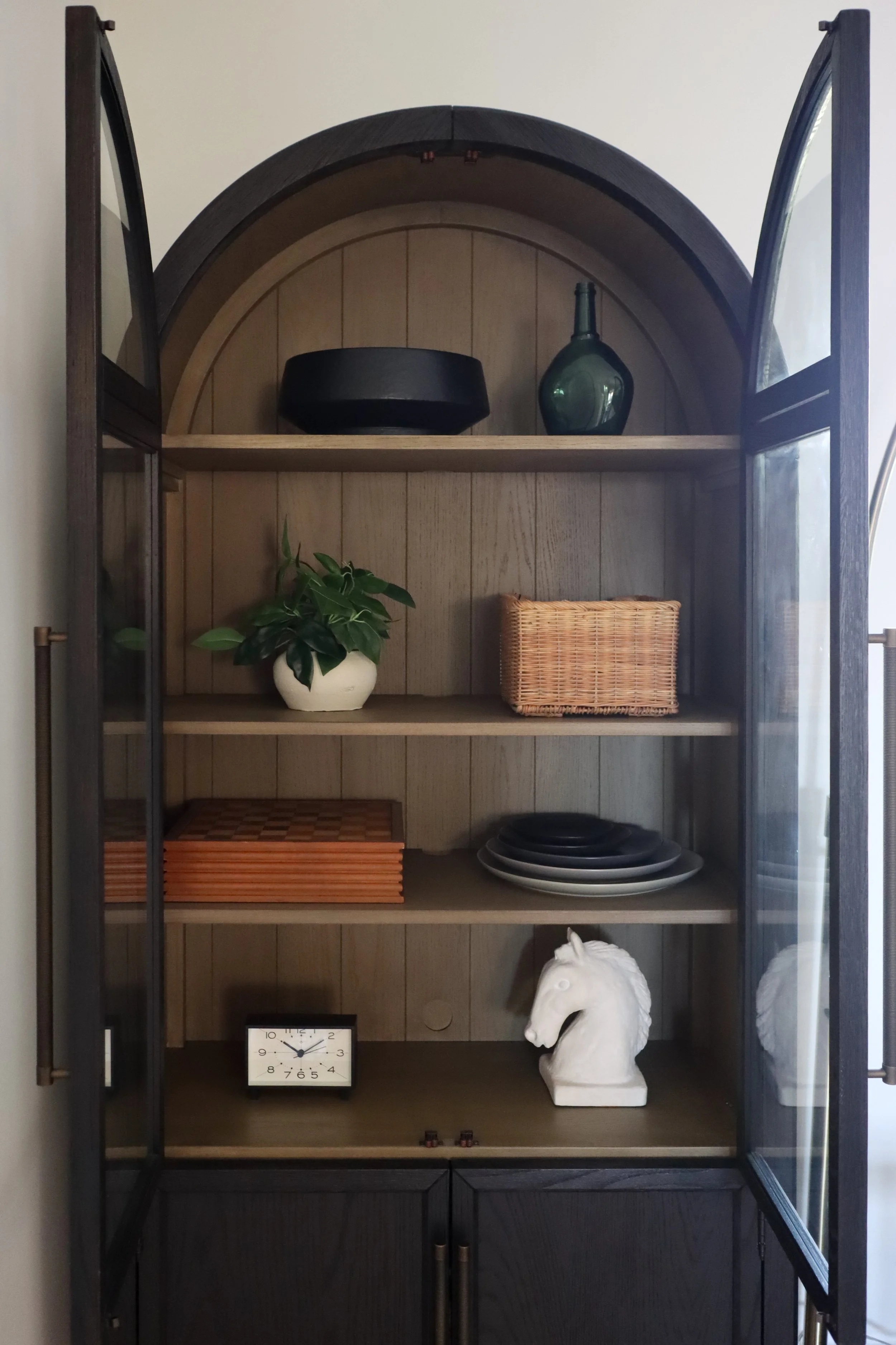 Close-up of a curved built-in bookcase styled with stacked books, ceramics, and decorative objects