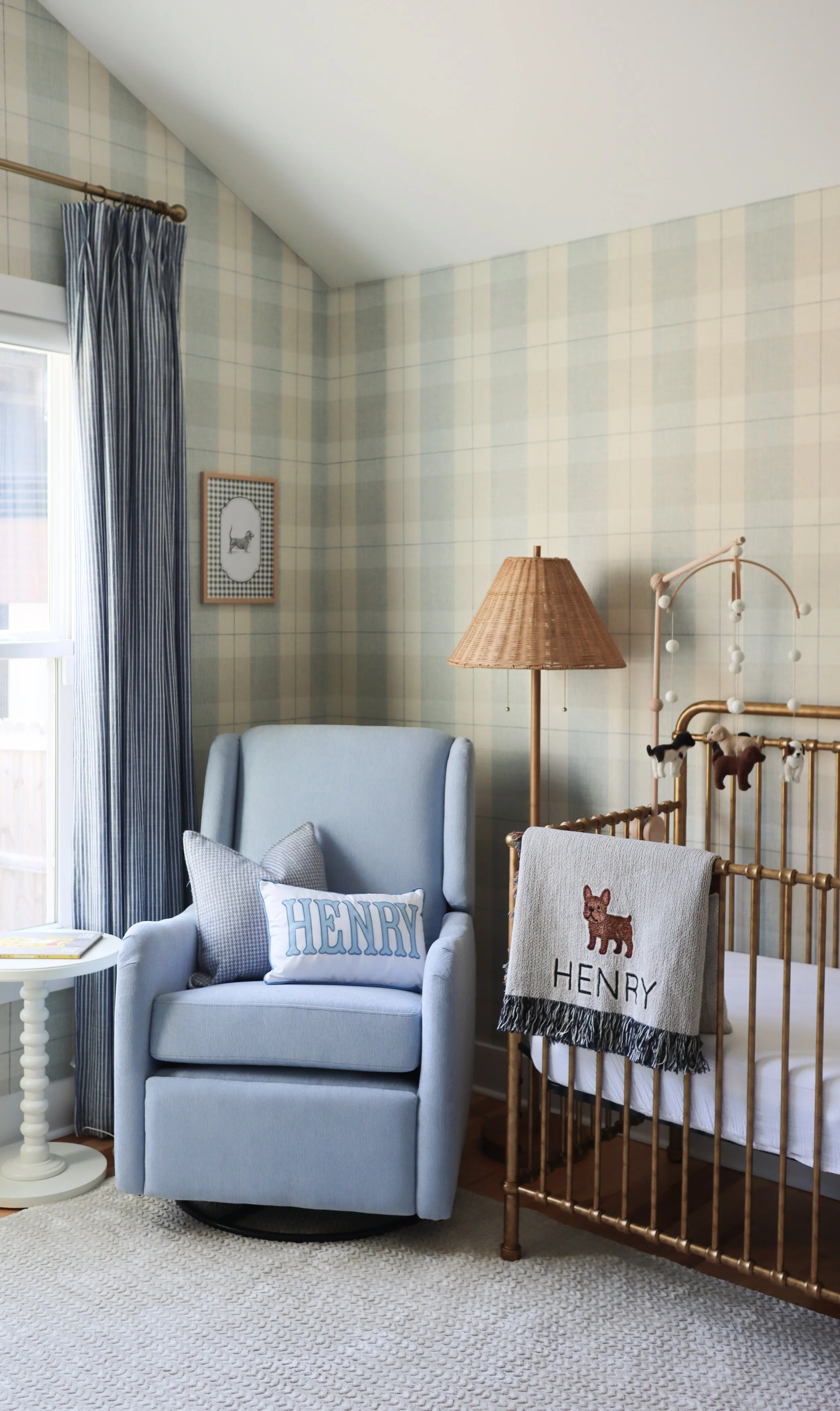 A soft blue nursery rocker creates a cozy corner for feeding, reading, and bonding moments with a custom name pillow adding a personalized touch.