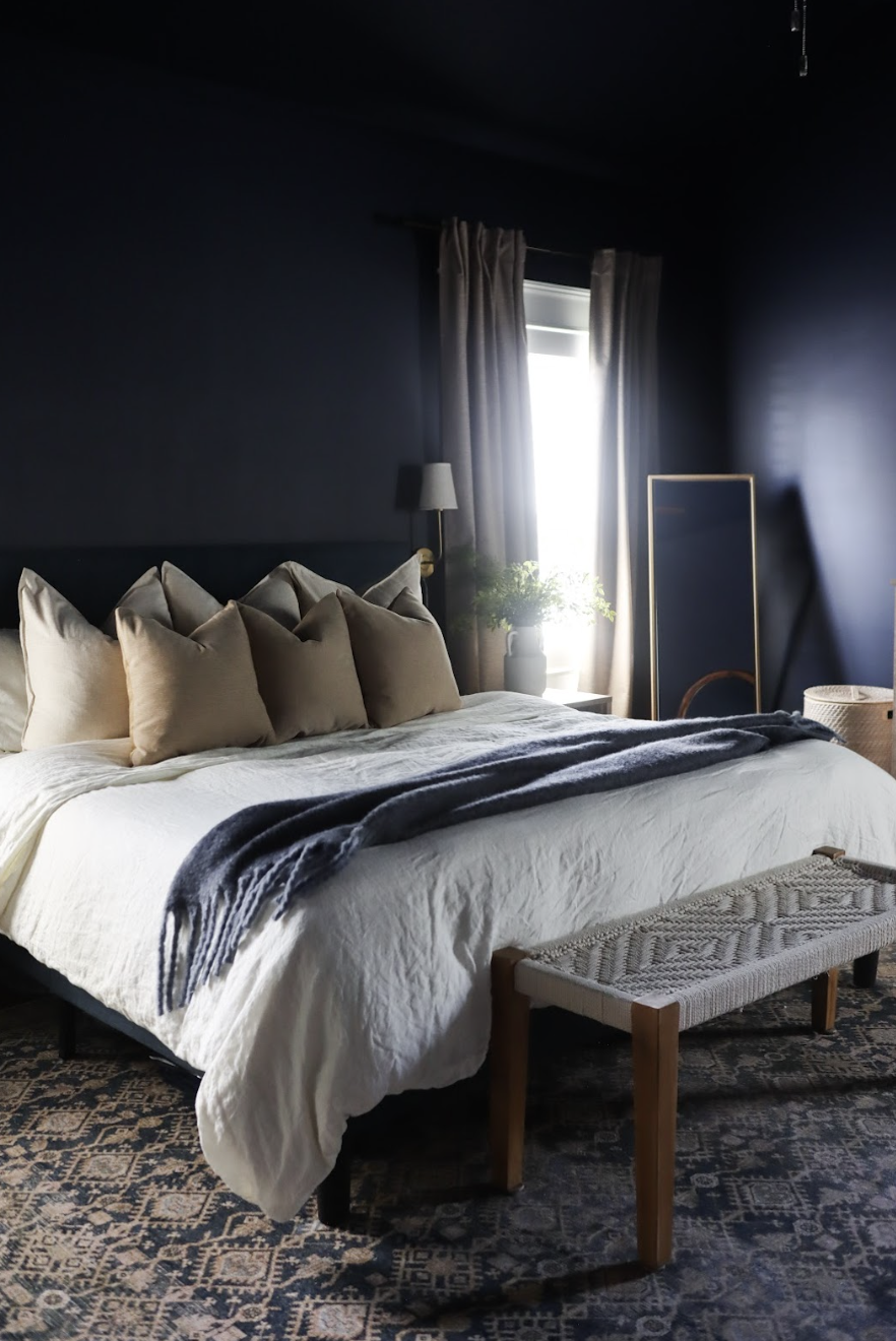 This primary bedroom was transformed into a cozy, balanced retreat with deep navy walls, organic textures, and light furnishings for a relaxed yet refined feel. By keeping a few existing pieces, the space feels both refreshed and familiar