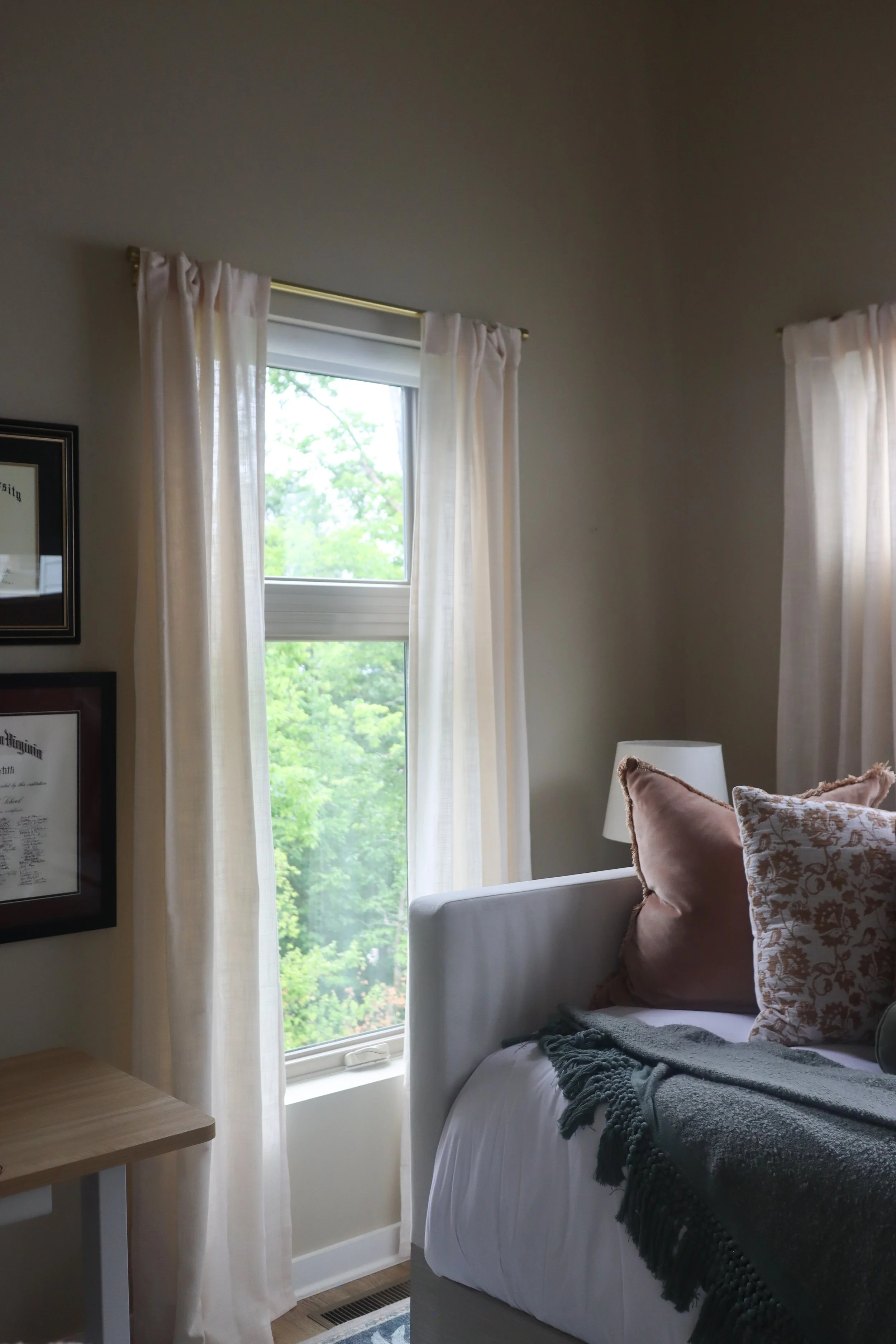 Soft beige curtains filtering natural light into the small but cozy guest room.