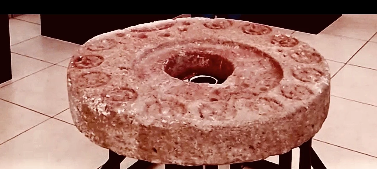 A large stone mill wheel on a stand, used for grinding grains in a kitchen.