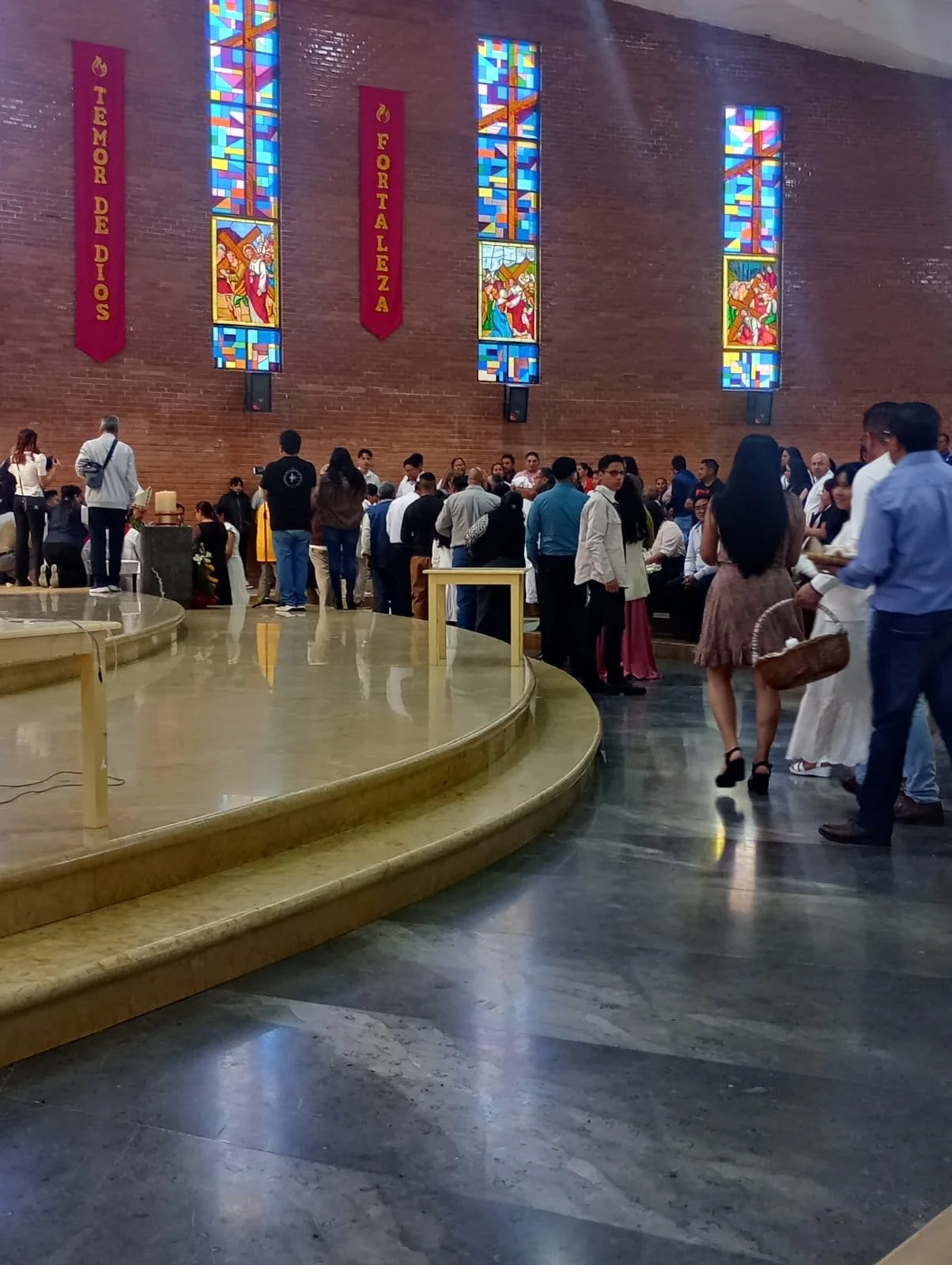 People gathered inside a church, with stained glass windows and religious banners on the wall.