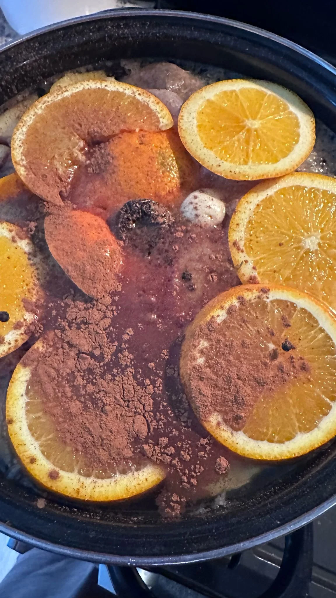 Orange slices and cocoa powder boiling in a pot.