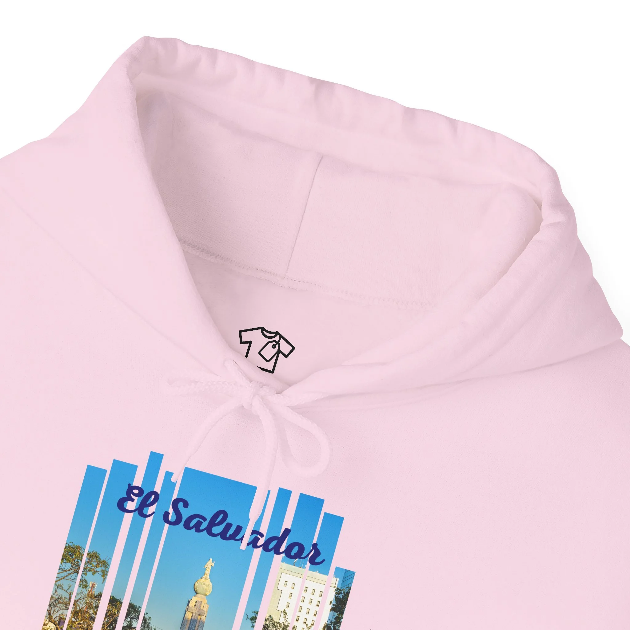 Close-up of a light pink hoodie with a graphic print that includes the text 'El Salvador' and an image of a cityscape with a monument and trees.