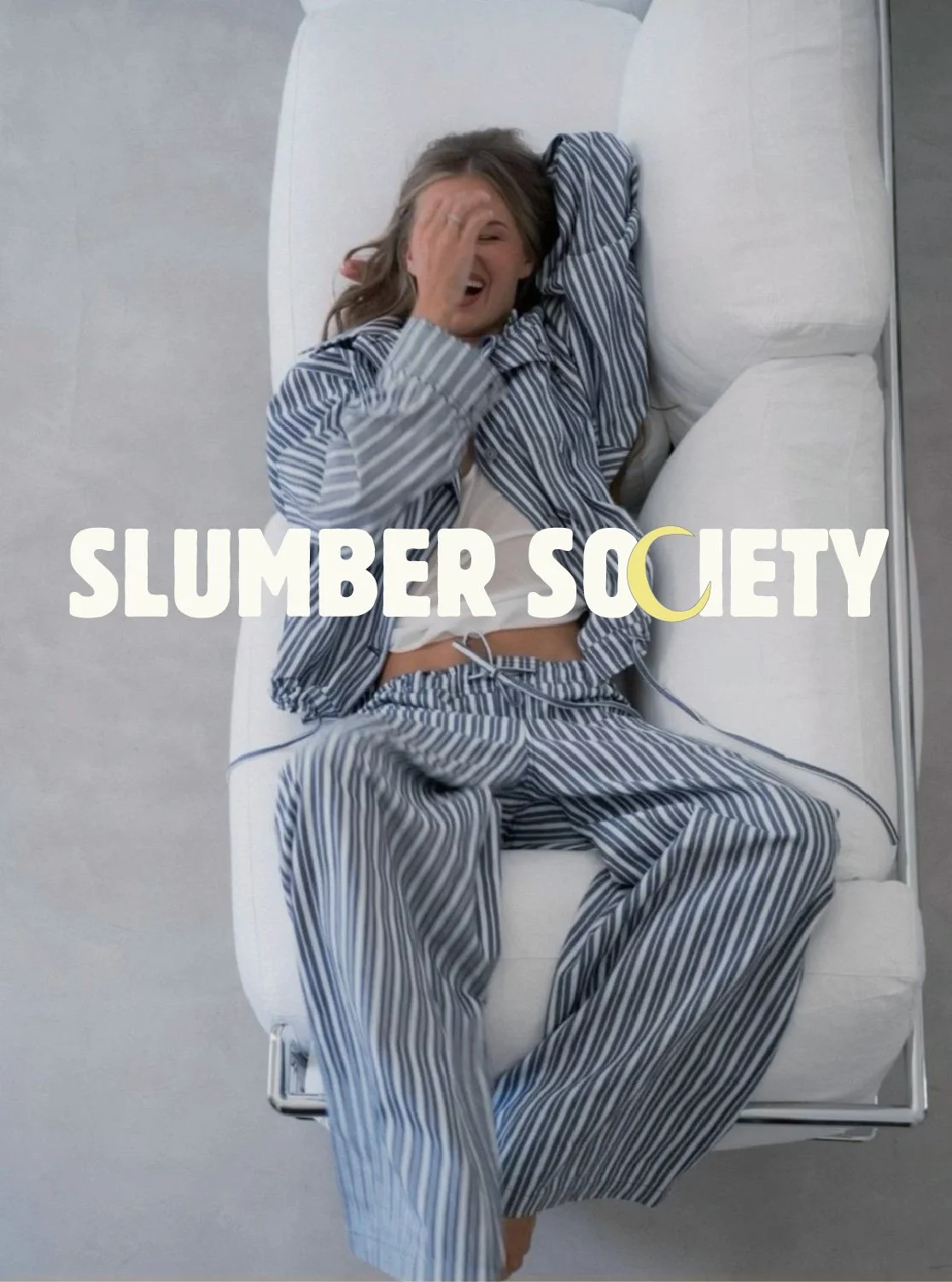 Woman on couch wearing Sleep Society sleepwear with the Sleep Society logo on top