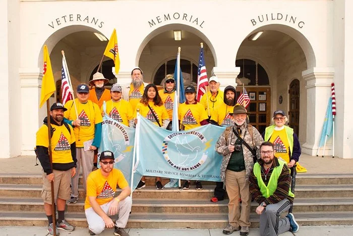 Group posed on the steps of the Veterans Memorial Building for the veterans day walk from Watsonville to Santa Cruz, some carrying flags.