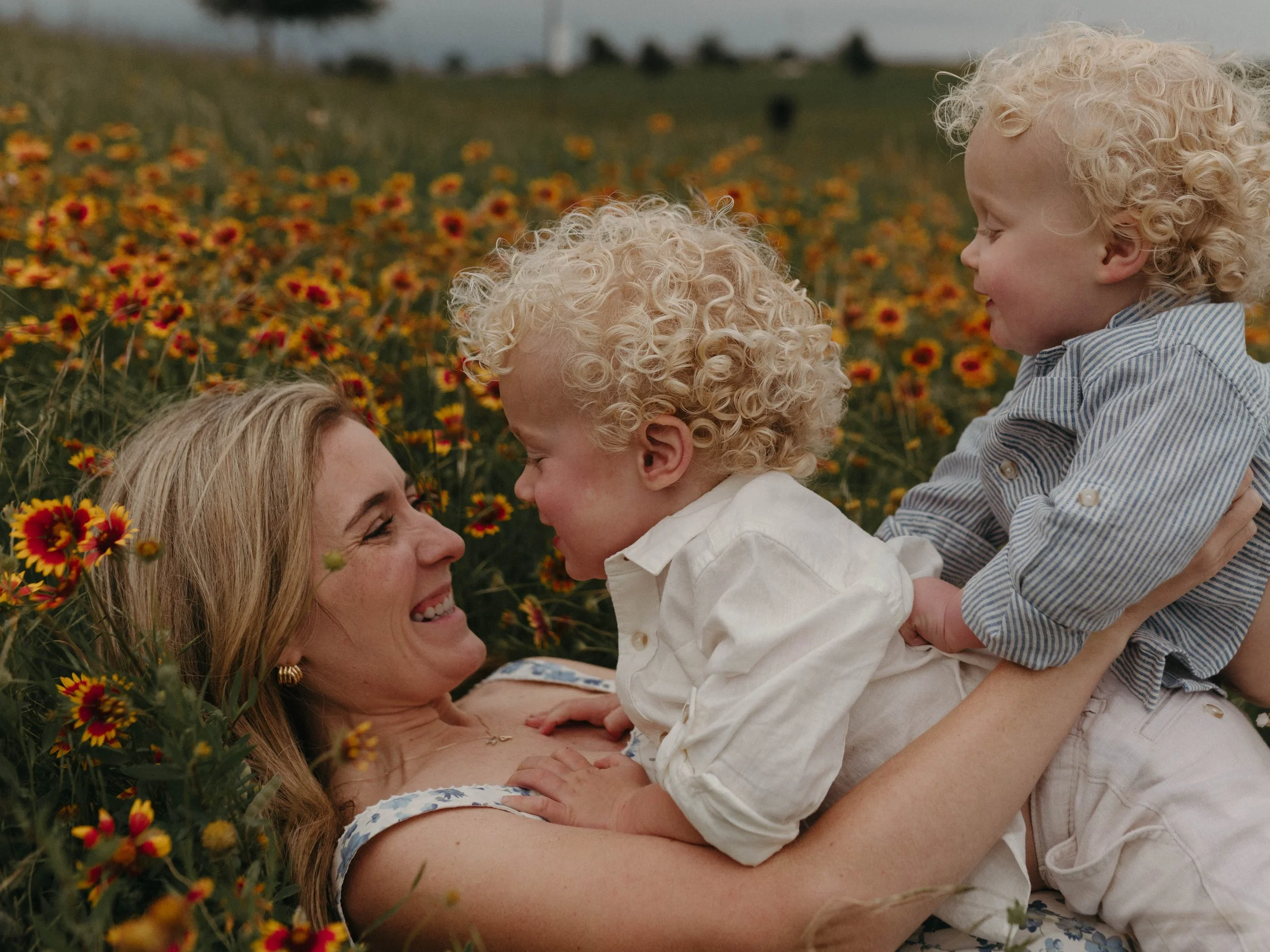 mom and 2 boys laying in the texas wild flowers in aledo texas during springtime