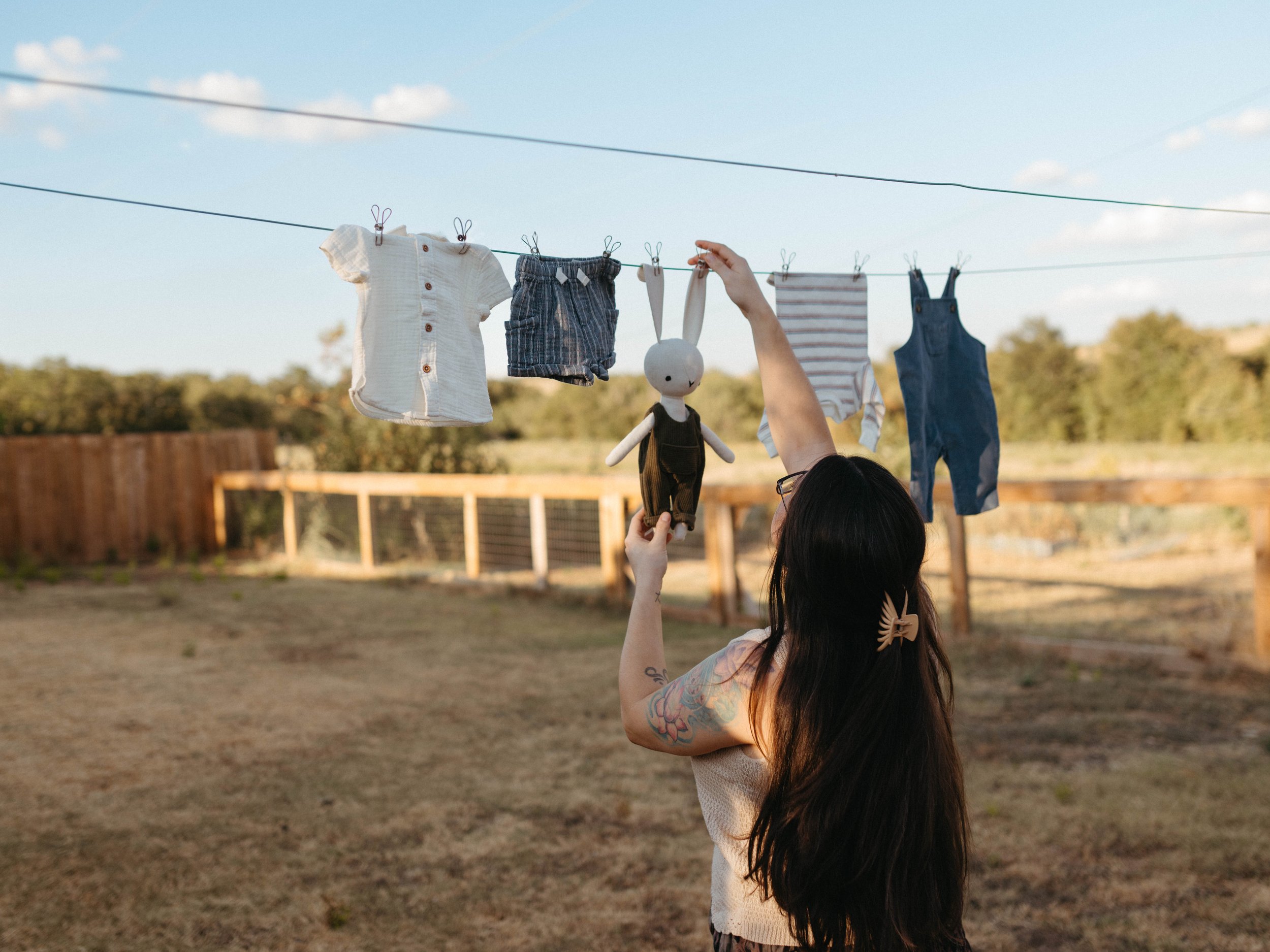 maternity photos of woman hanging clothes on her clothes line in backyard of aledo, tx