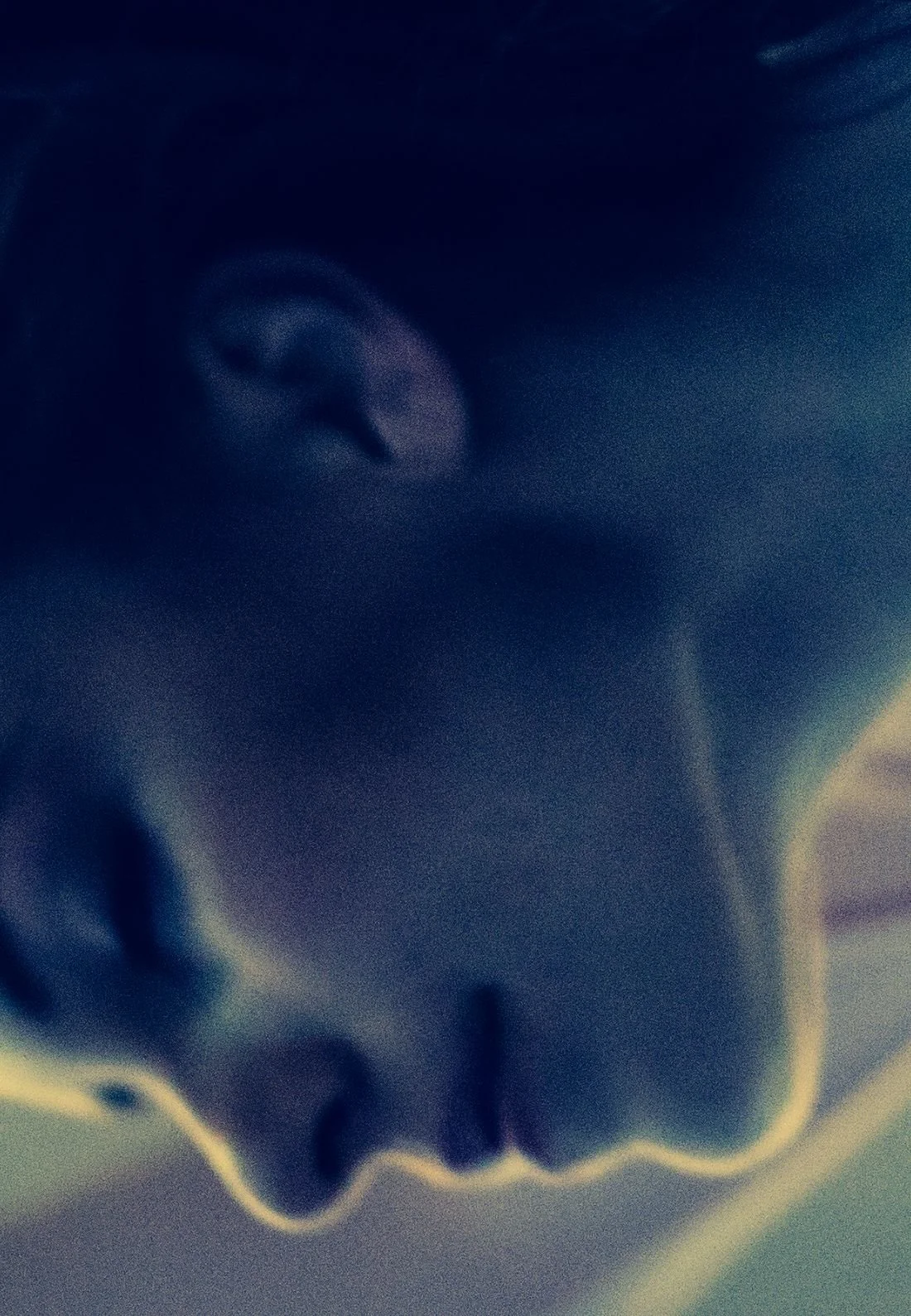 A dancer’s face in close-up, washed in blue light