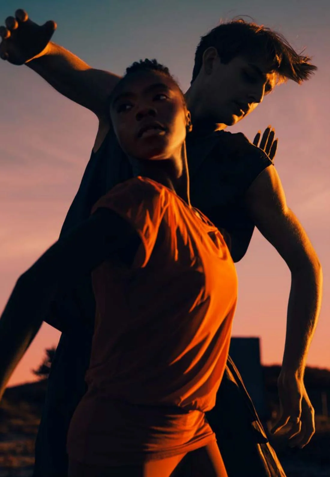 Two dancers lit orange at sunset