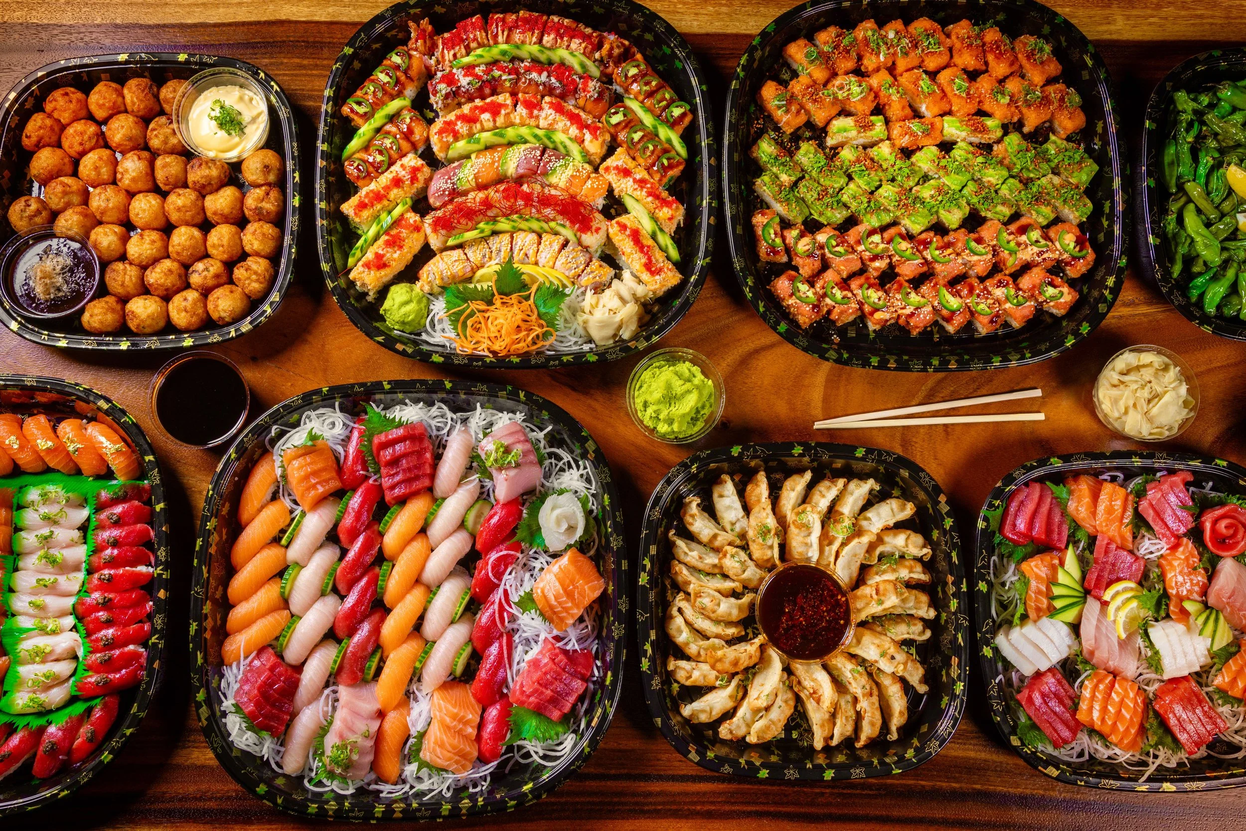 Assorted sushi and sashimi platter with various rolls, nigiri, and garnishes on a wooden table