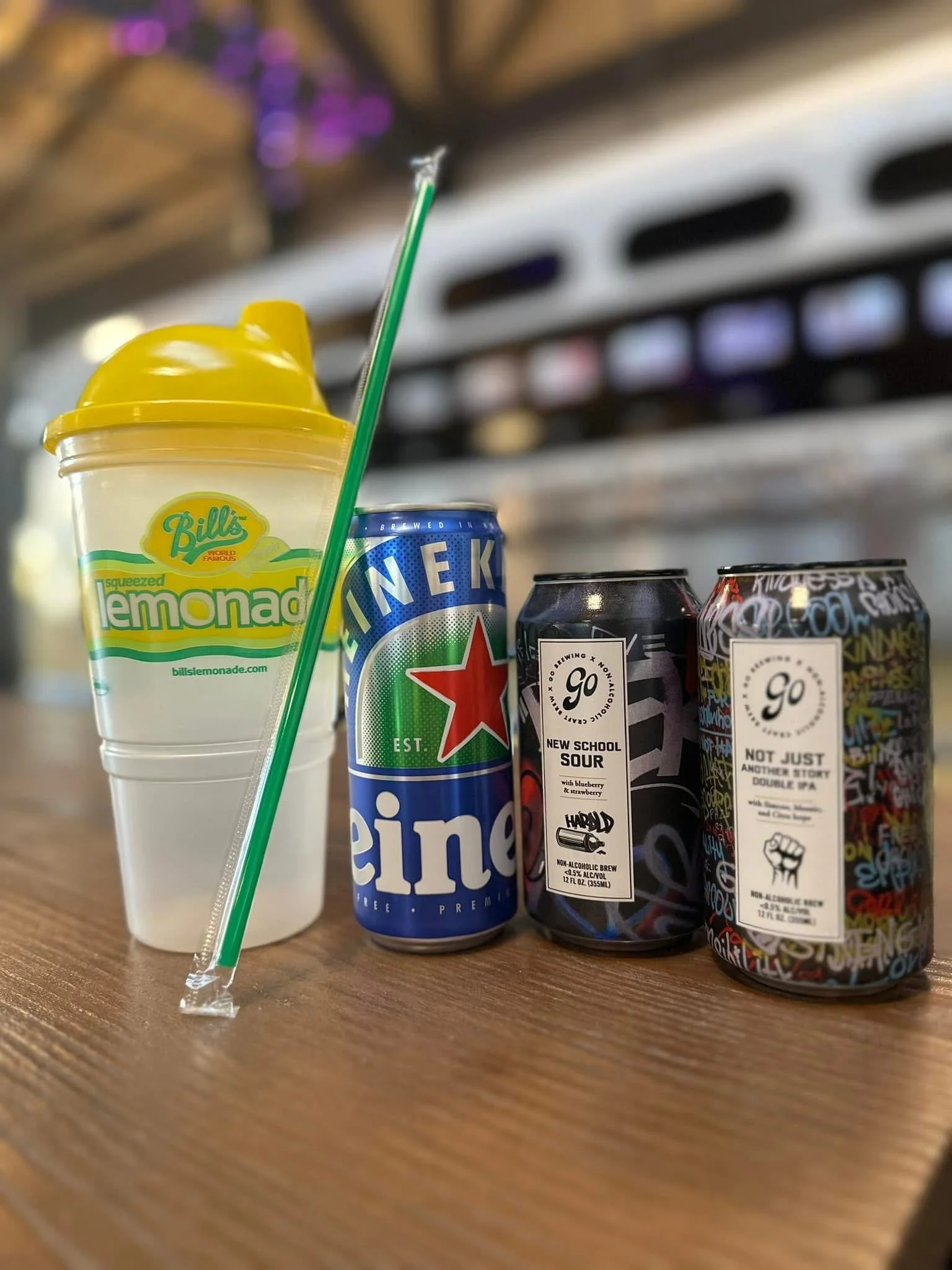 A collection of canned non-alcoholic beers and a lemonade on a wooden table.