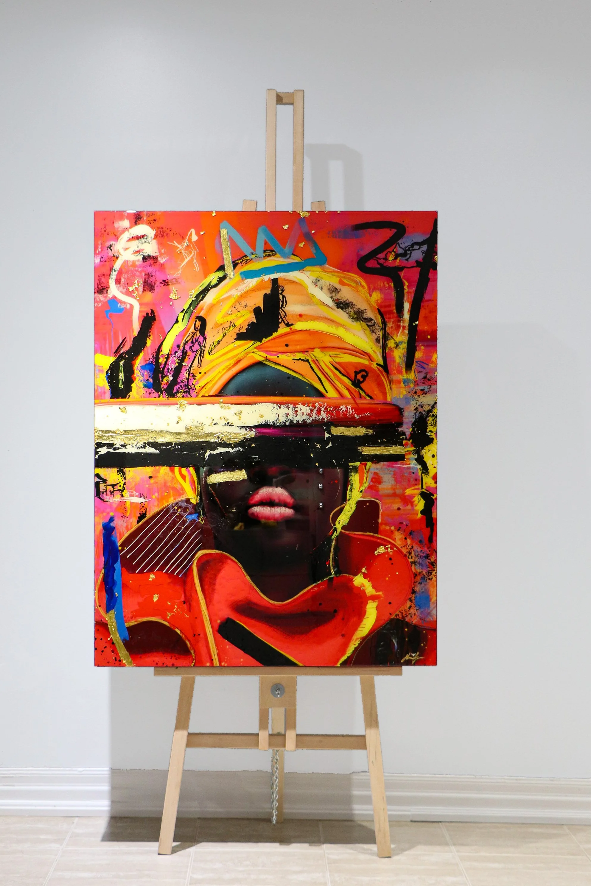 Colorful abstract artwork on an easel featuring a woman with lips and a hat, with graffiti-like marks and splashes of paint in vibrant colors.
