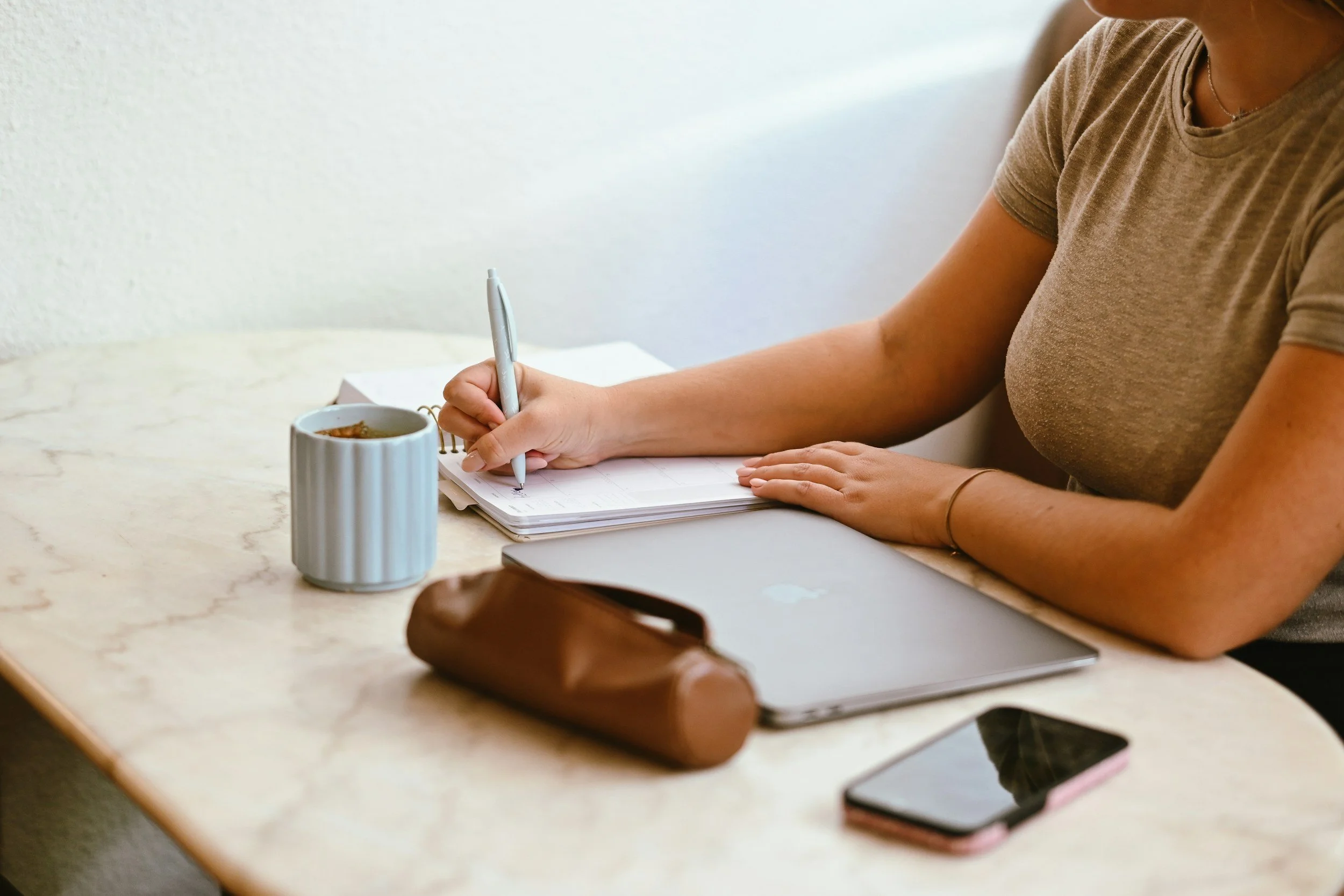Therapist writing in her planner, mapping out a hybrid transition from insurance to private pay clients