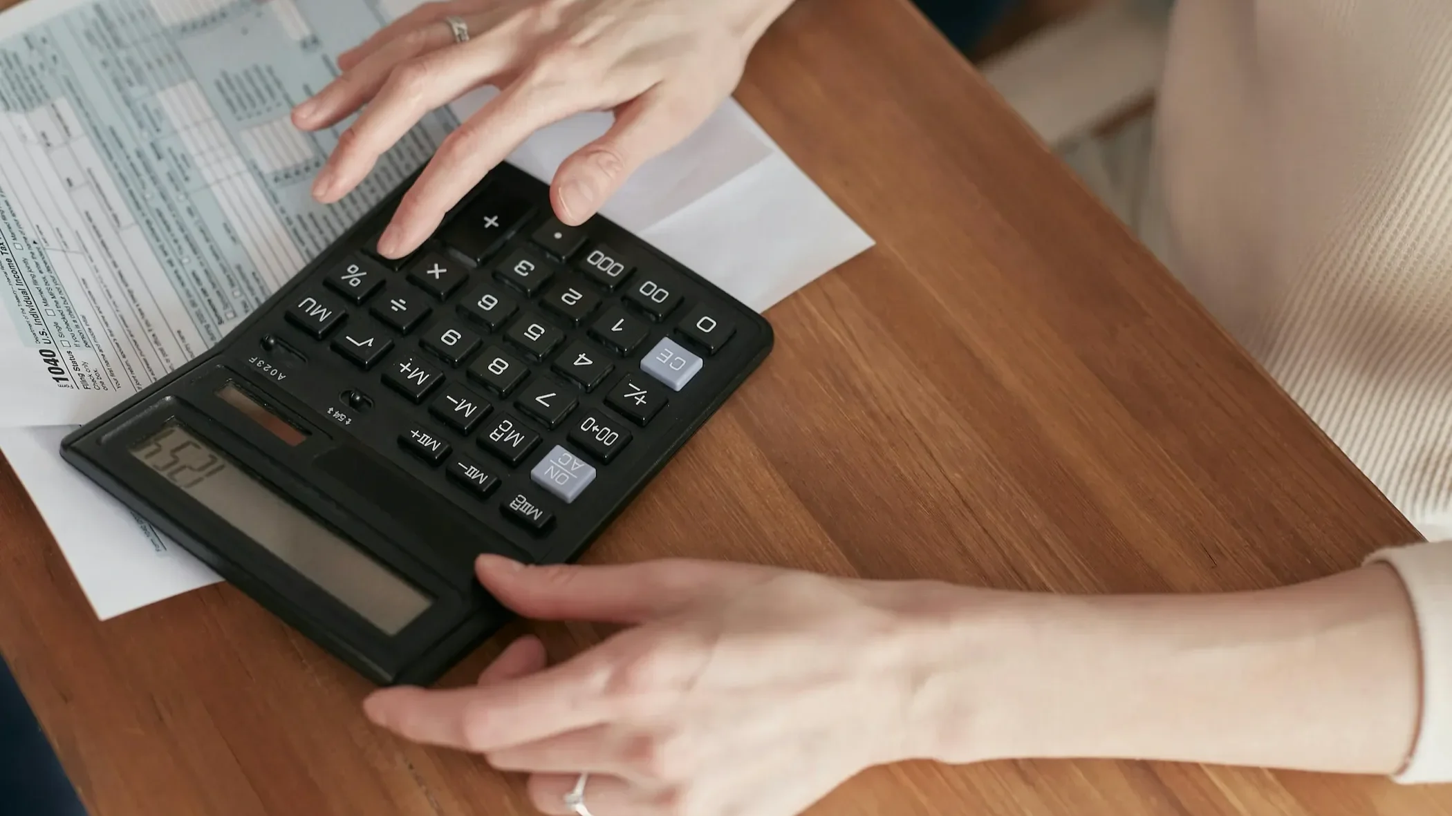 Woman pressing buttons on a calculator, visually representing the importance of budgeting and financial planning for travel.