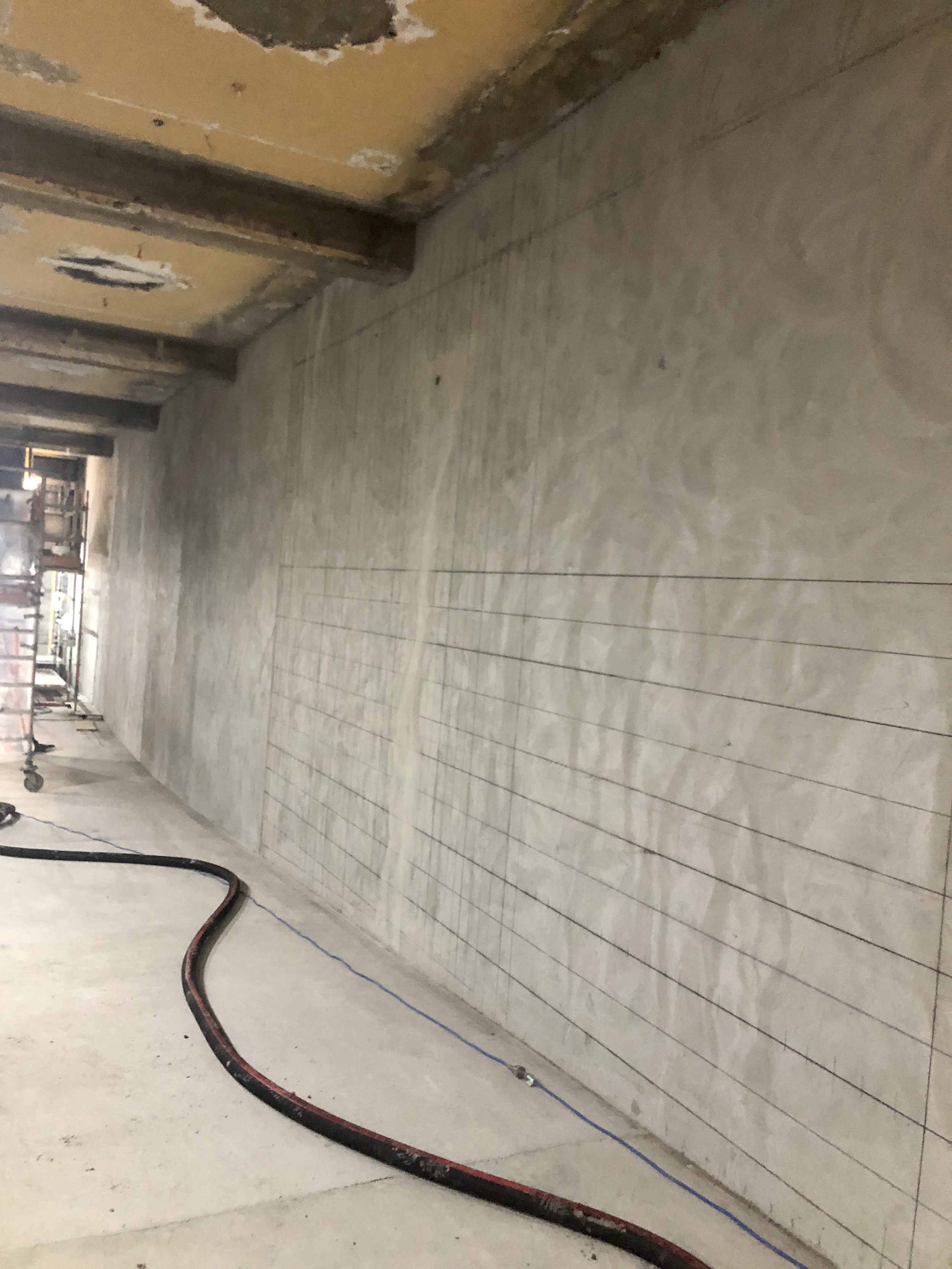 Construction area with tiled floor, partially installed tiles, construction wires, and piping on the floor.