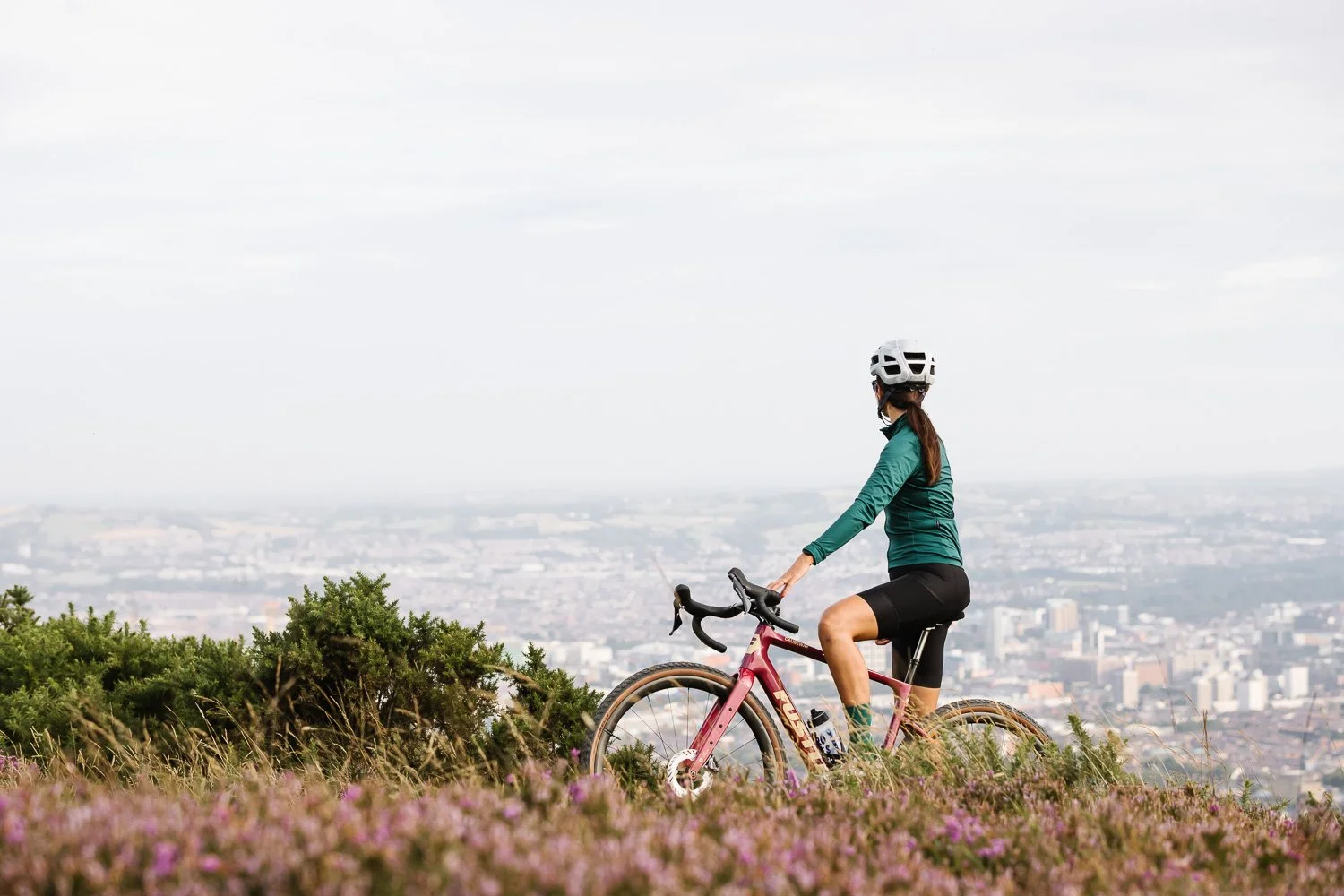 Female cyclist on Fustle Causeway gravel bike with view of Belfast