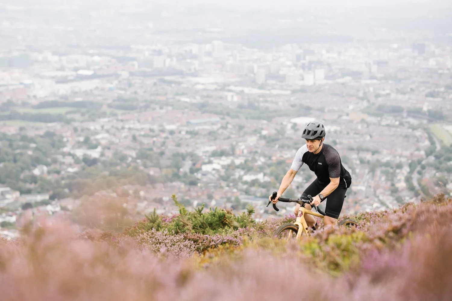Male cyclist on Fustle Causeway gravel bike with view of Belfast