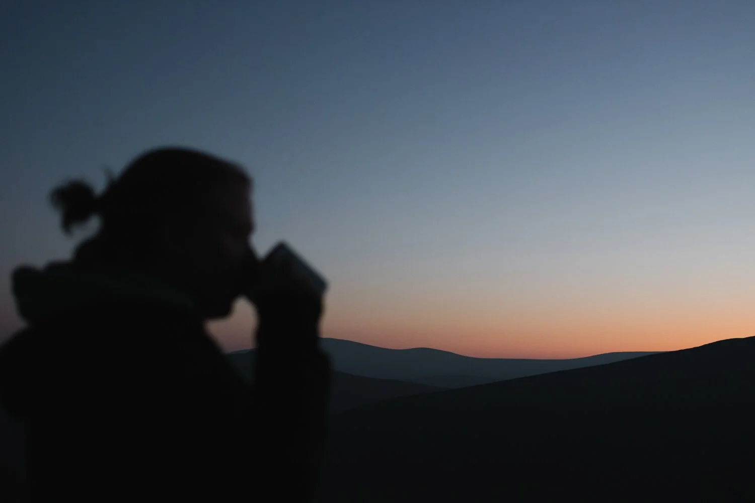 Female hiker enjoying sunset above Lough Tay in Wicklow mountains