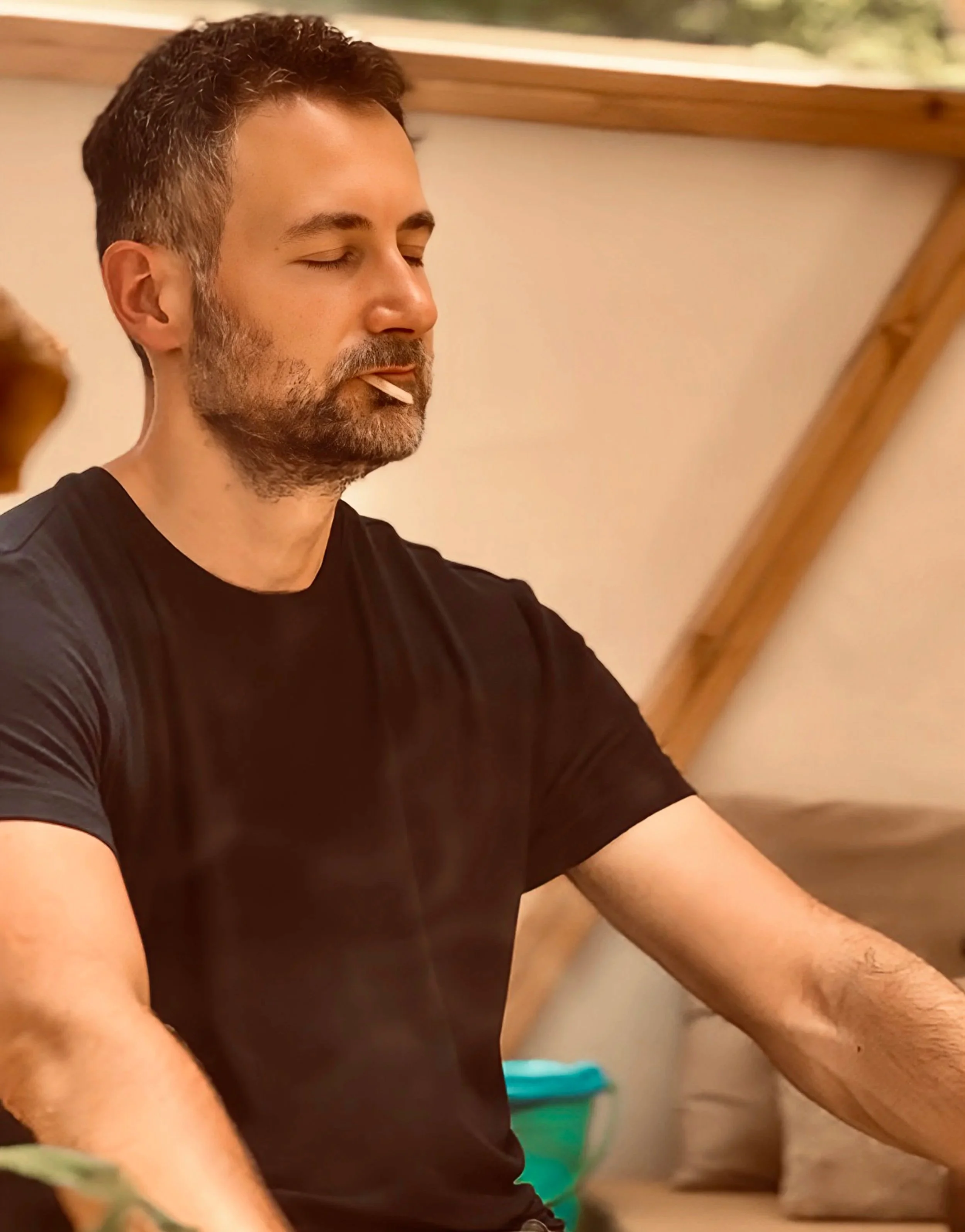 A man with short dark hair and a beard meditating.