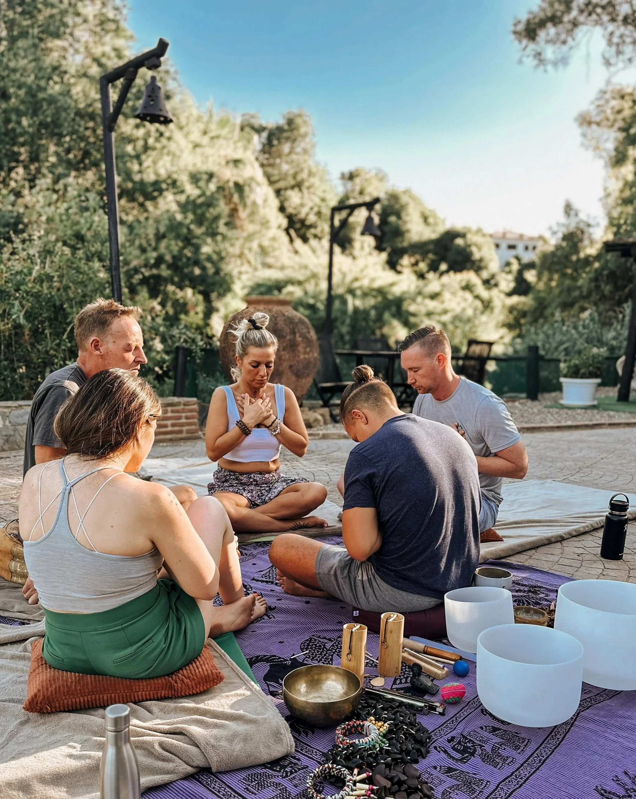 Group of six people sitting on a blanket on a sharing in a traditional ceremony.