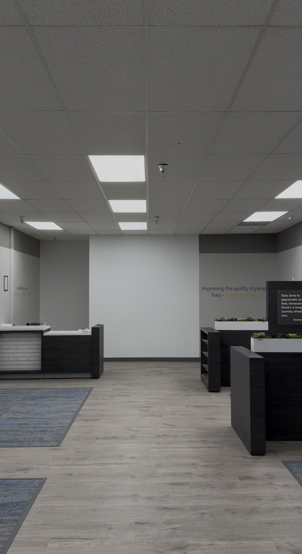 Empty reception area with black counters, potted plants, and a wall with motivational text
