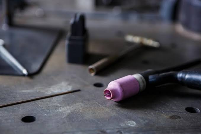Collection of spray paint nozzles and tools organized on a white surface. Pink container tubes labeled with numbers, black spray nozzles, and bronze-colored components.