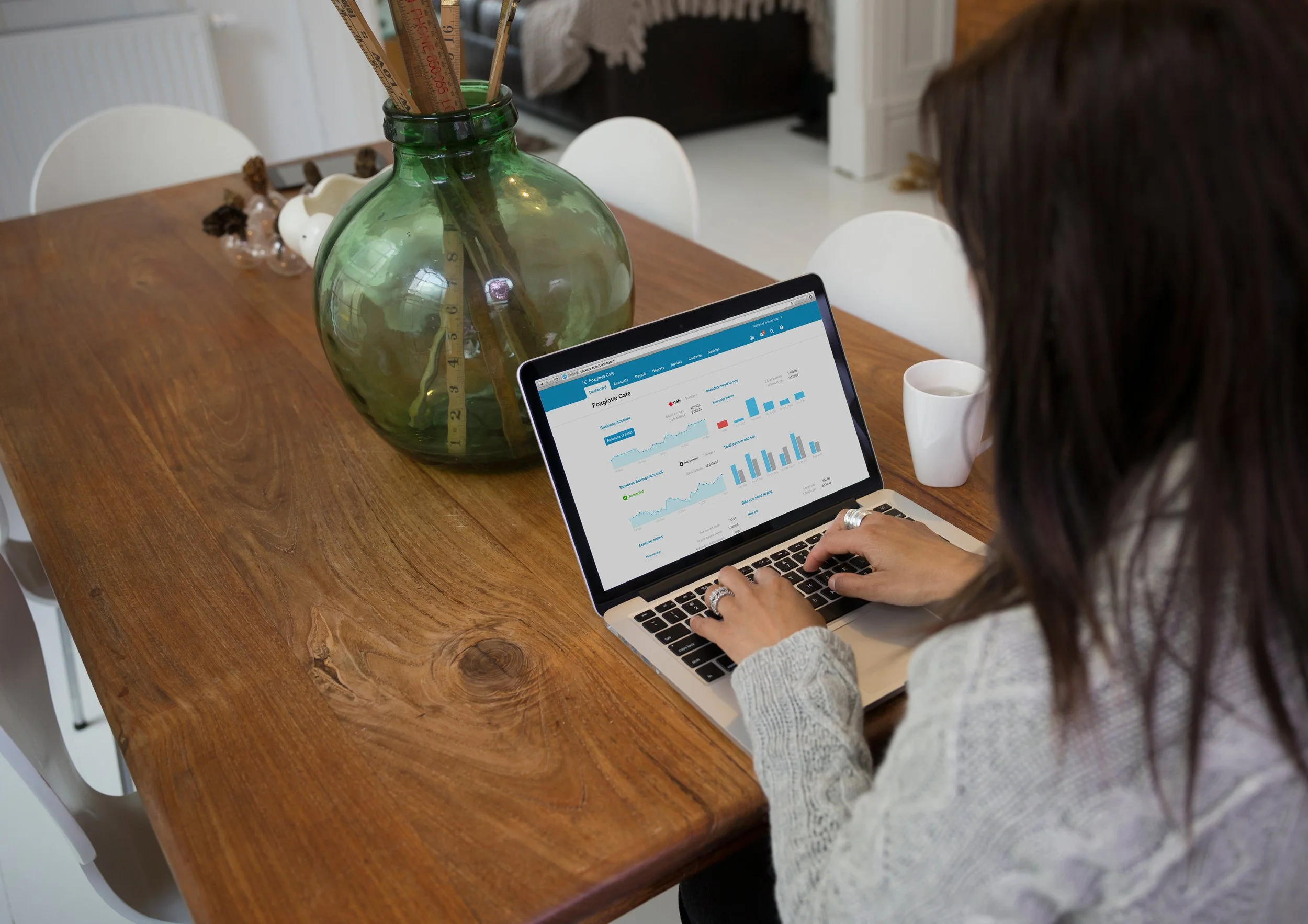 Person working on a laptop, using Xero accounting software, displaying analytics charts and graphs in a home office setting.