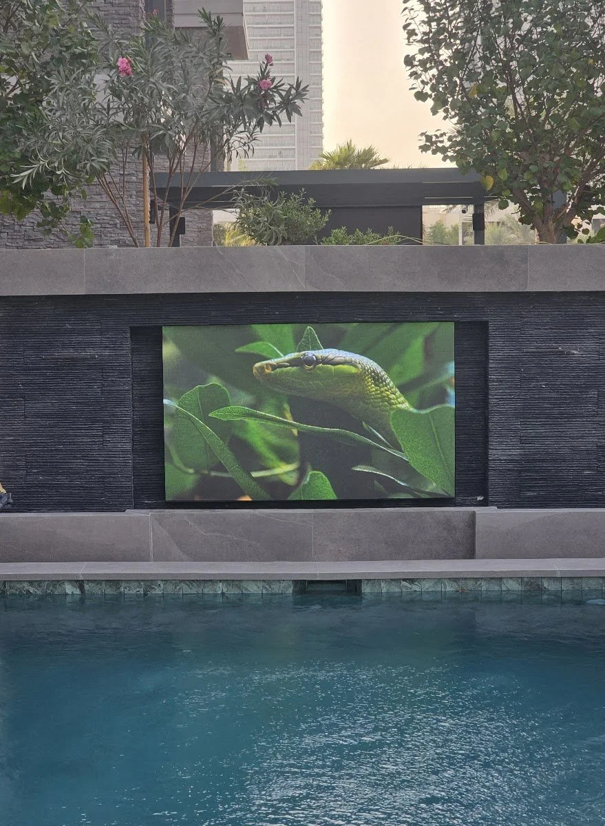 Outdoor TV built into a stone wall beside a Dubai villa pool