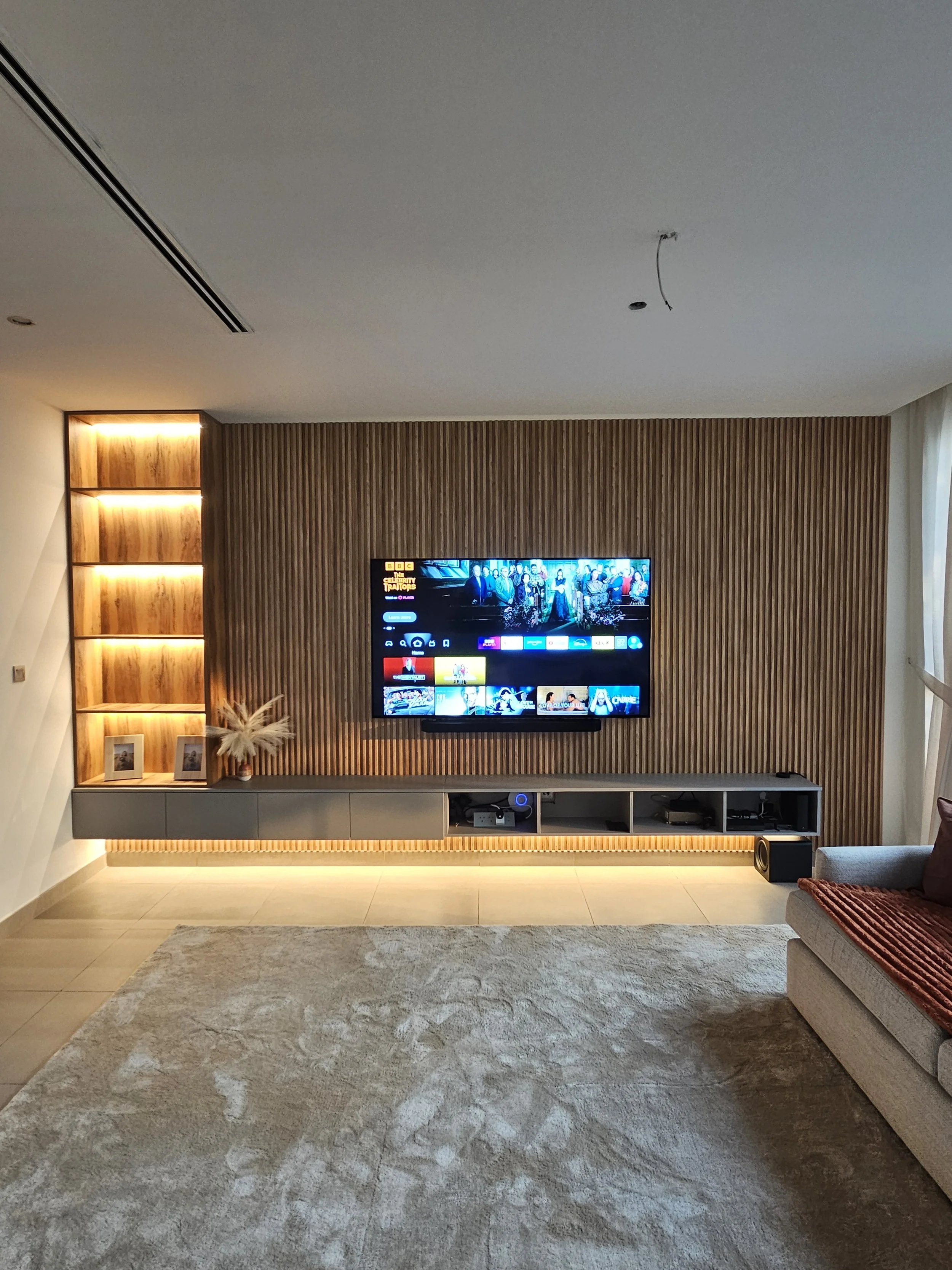 Fluted timber media wall with LED lighting and a large TV in a Dubai home