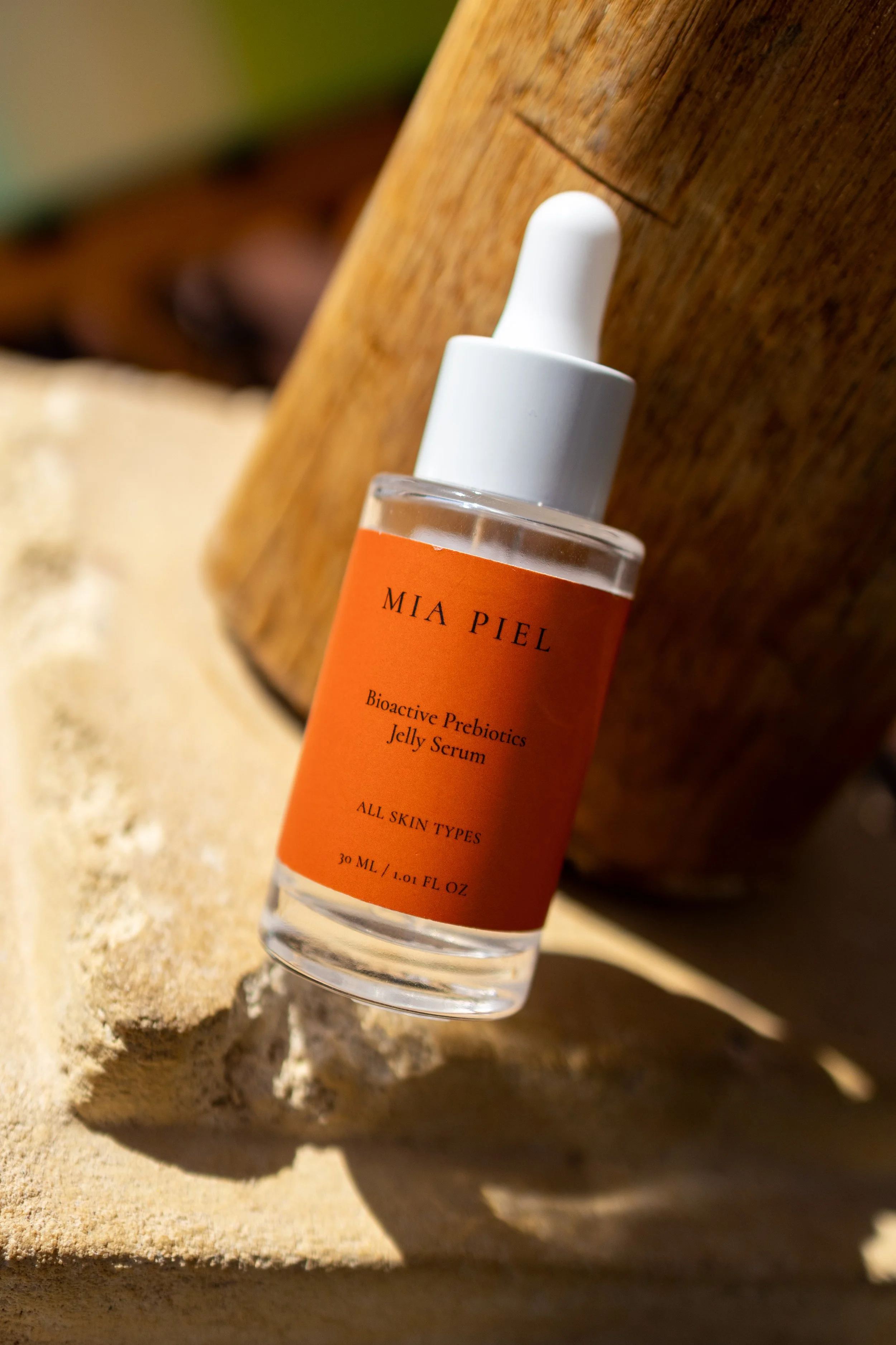 Mia Piell bioactive prebiotic jelly serum in an orange-labeled bottle on a wooden surface