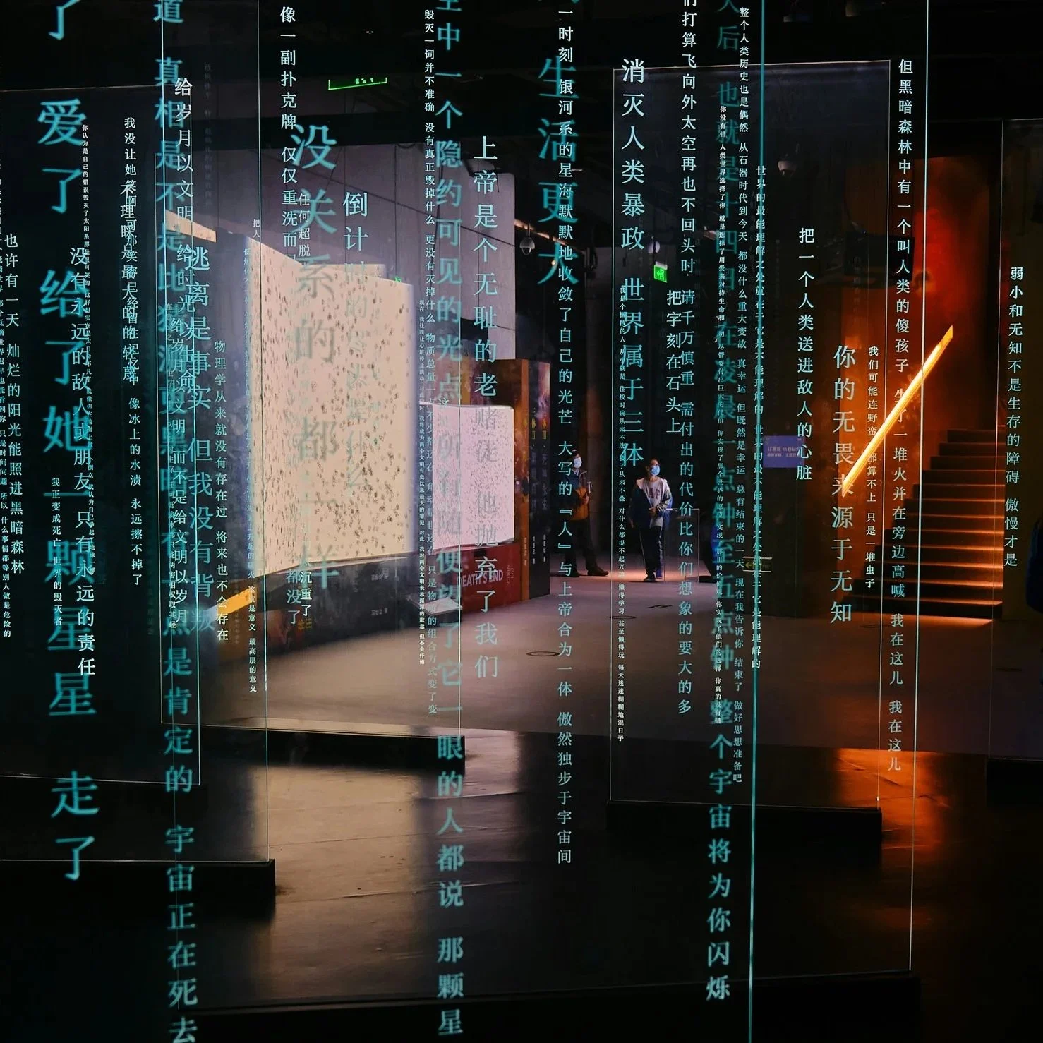 Ausstellung mit digitalen chinesischen Texten und Bildern, in einem dunklen Raum mit beleuchteten Textwänden und Treppen.