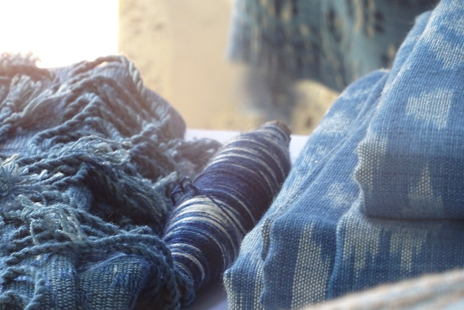 Textile en laine, fil, et tissu en denim bleu sur un fond flou.