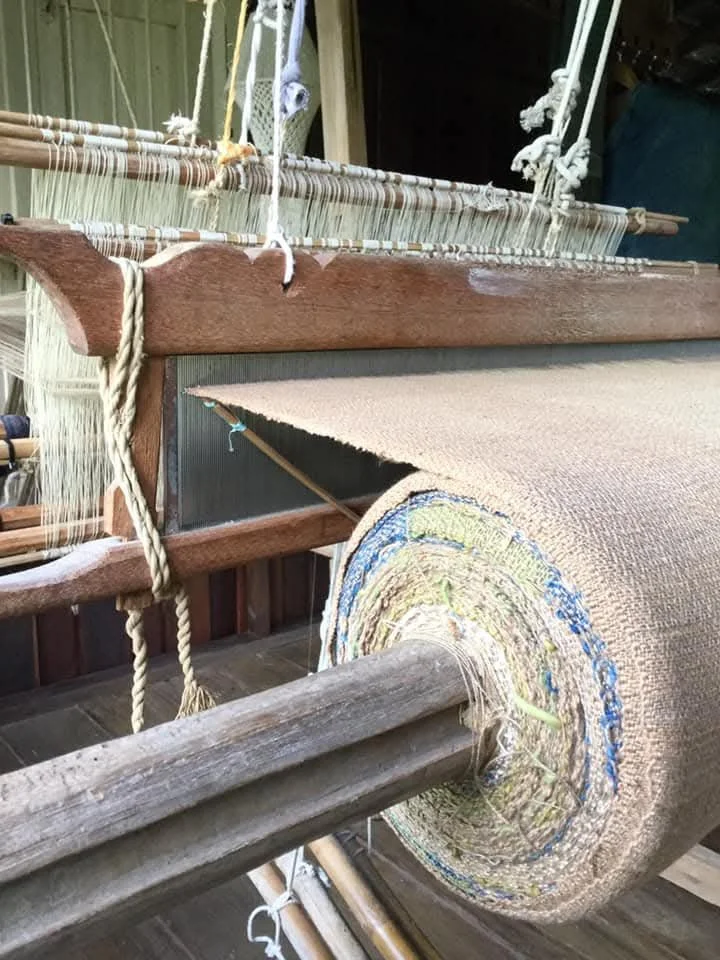 Un métier à tisser en bois avec une bobine de fil ou de tissu enroulée dessus, utilisé pour fabriquer des textiles.