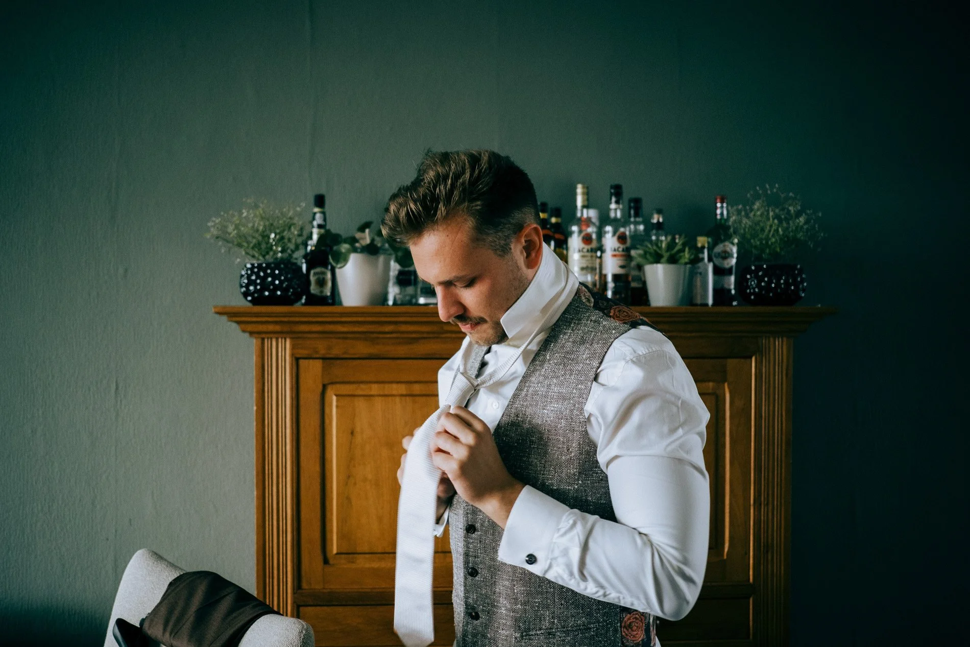 A groom adjusts his tie during quiet wedding morning preparations, captured in natural light with a relaxed, intimate atmosphere by Quiet Mornings Wedding Photography in Scotland.